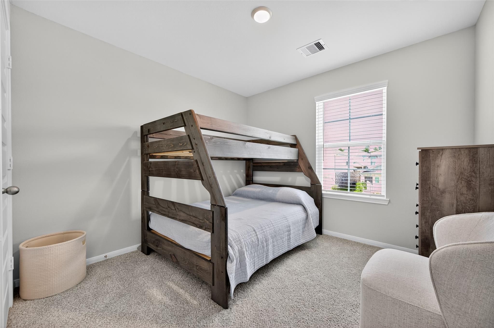 Rustic wooden bunk bed with bedding in cozy gray-walled bedroom, dresser, armchair in 5-bedroom Davidson Homes The Brazos E, Magnolia TX