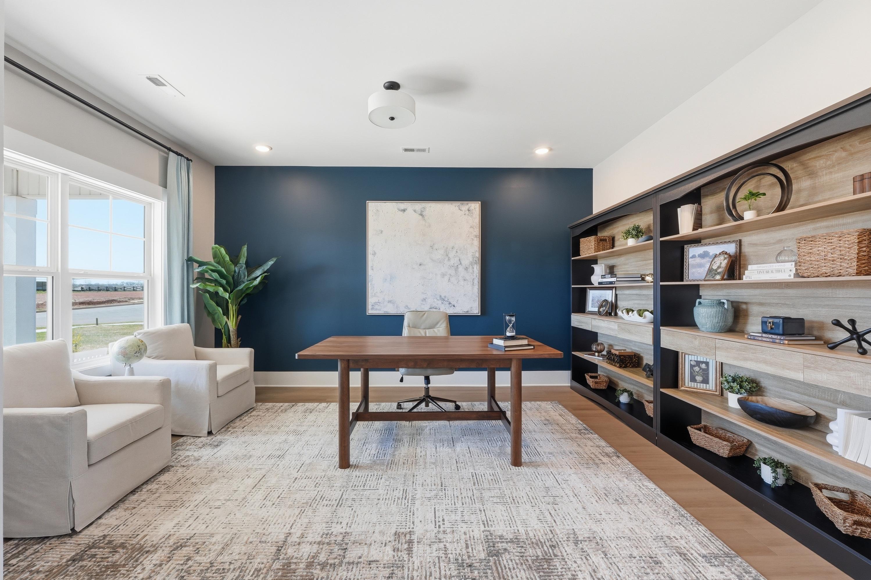 Cozy home office in Berry Cove New Market Alabama featuring navy walls wooden desk built-in bookshelves and armchairs