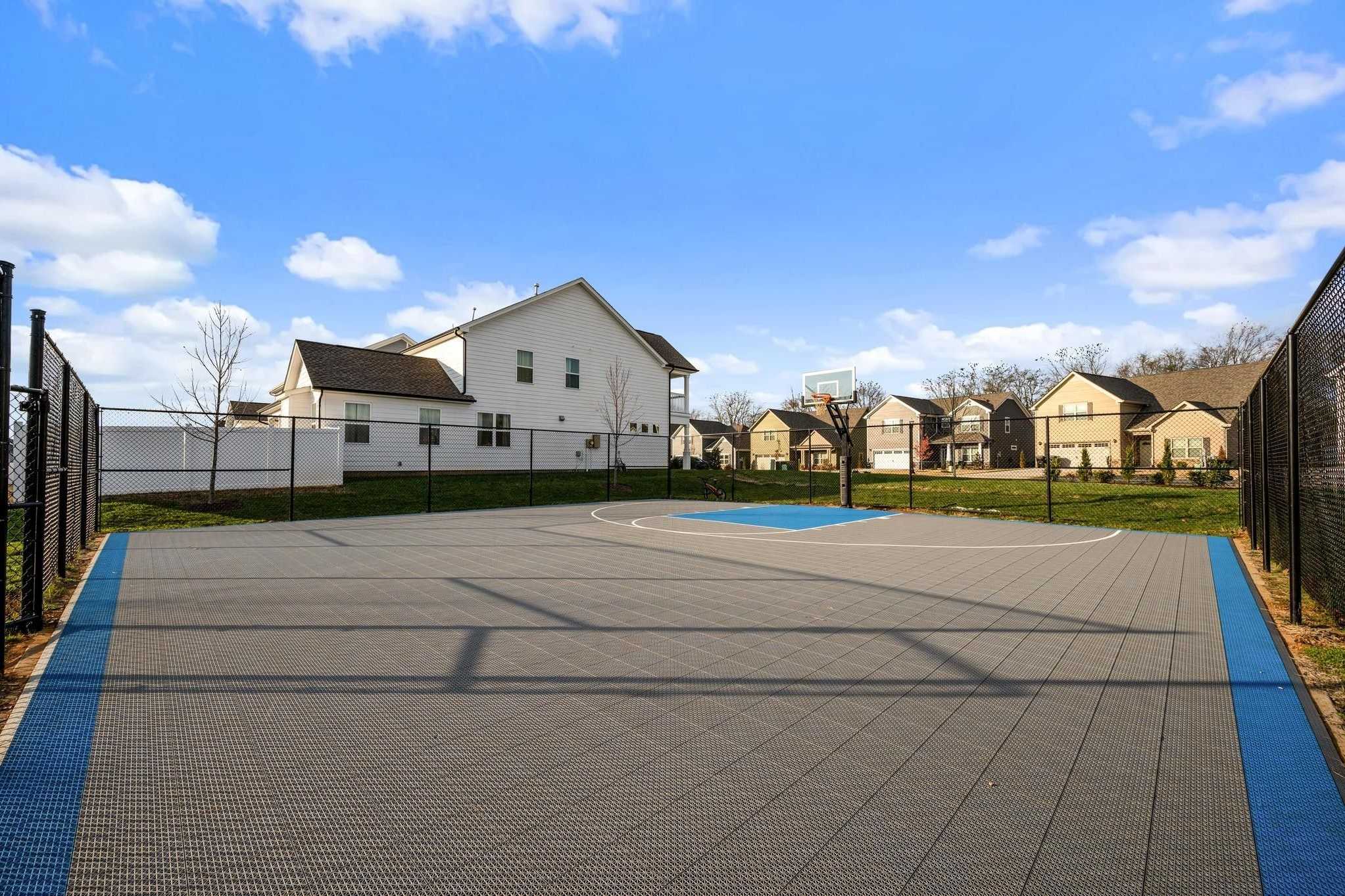 Community basketball court at Shelton Square in Murfreesboro TN with gray surface blue edges hoop and surrounding homes