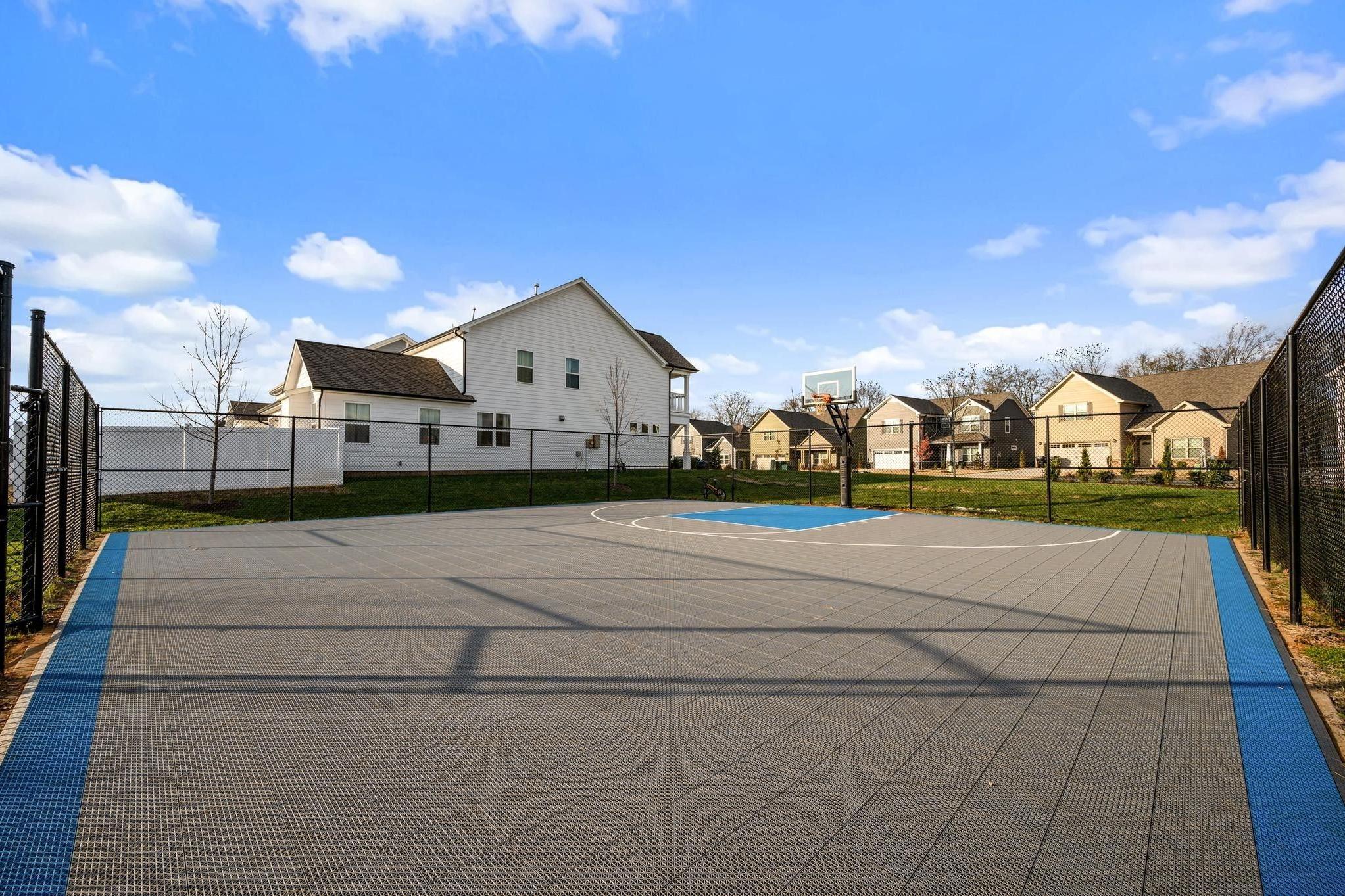 Community basketball court at Shelton Square in Murfreesboro TN with gray surface blue edges hoop and surrounding homes