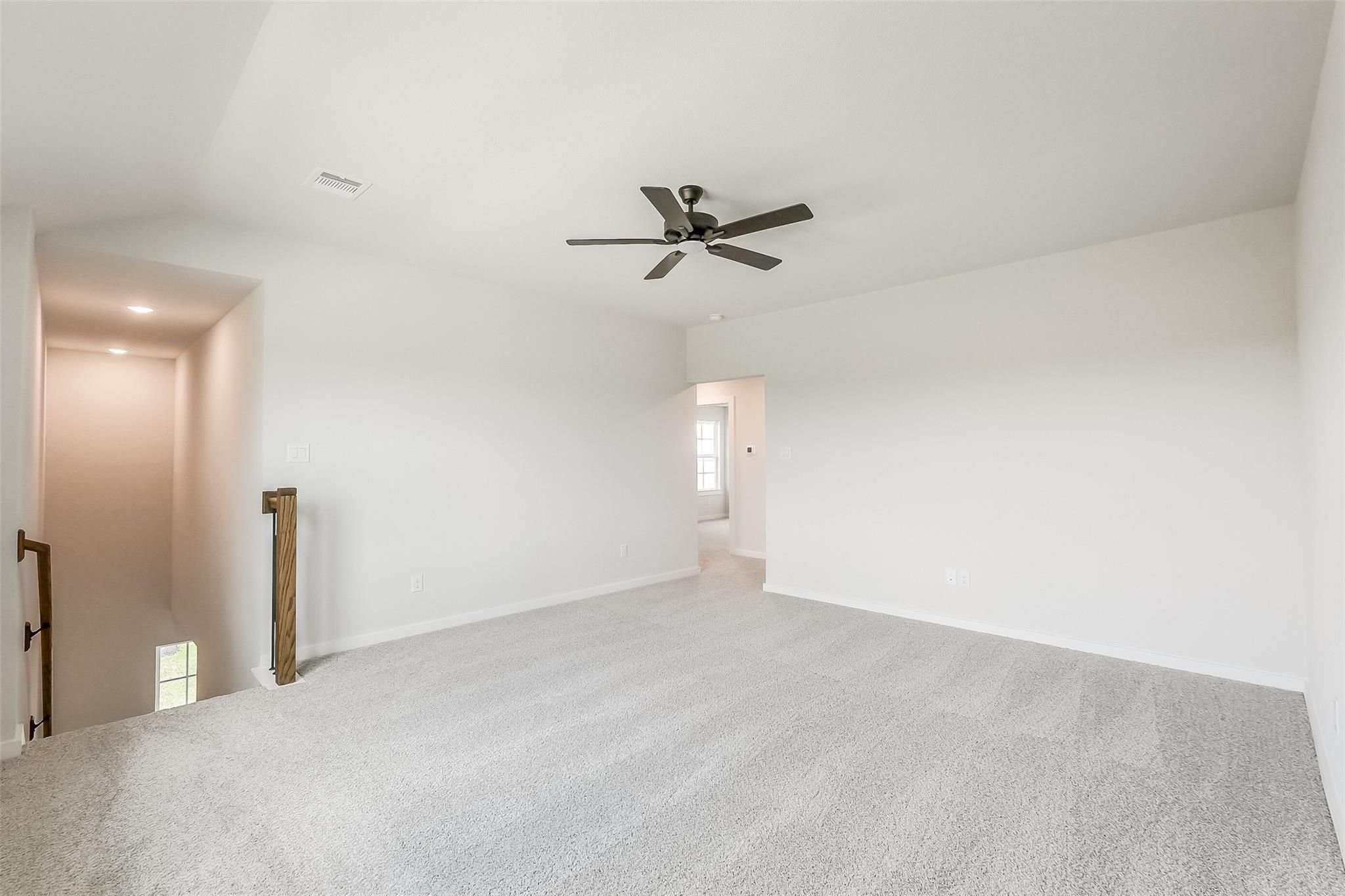 Spacious upstairs loft with ceiling fan, carpeted floors, and wooden staircase in Davidson Homes The Tierra B, Beasley, Texas
