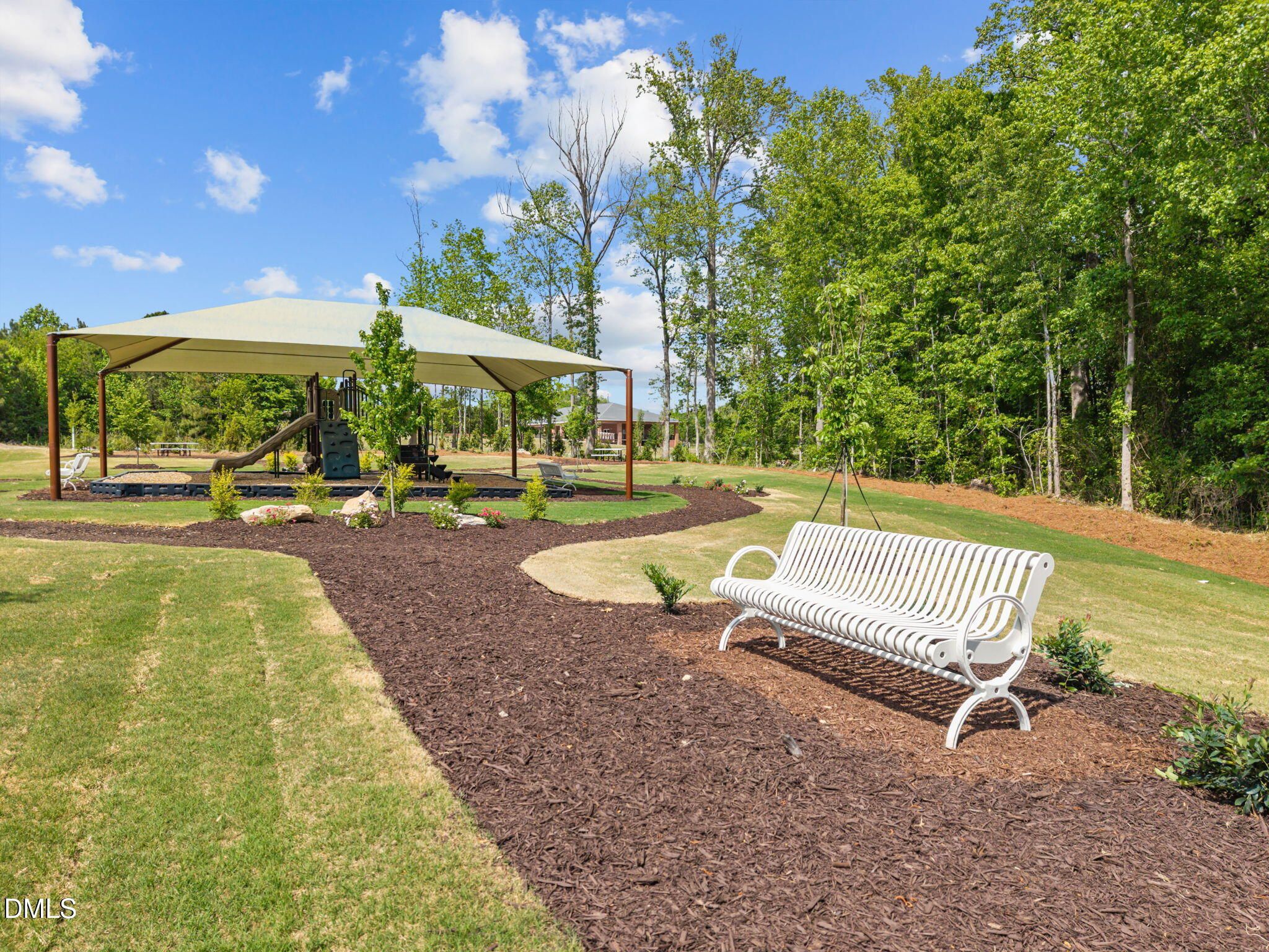 Serene playground with slide and pavilion, white swing bench on mulch paths amid trees in Wendell Ridge, Wendell, North Carolina