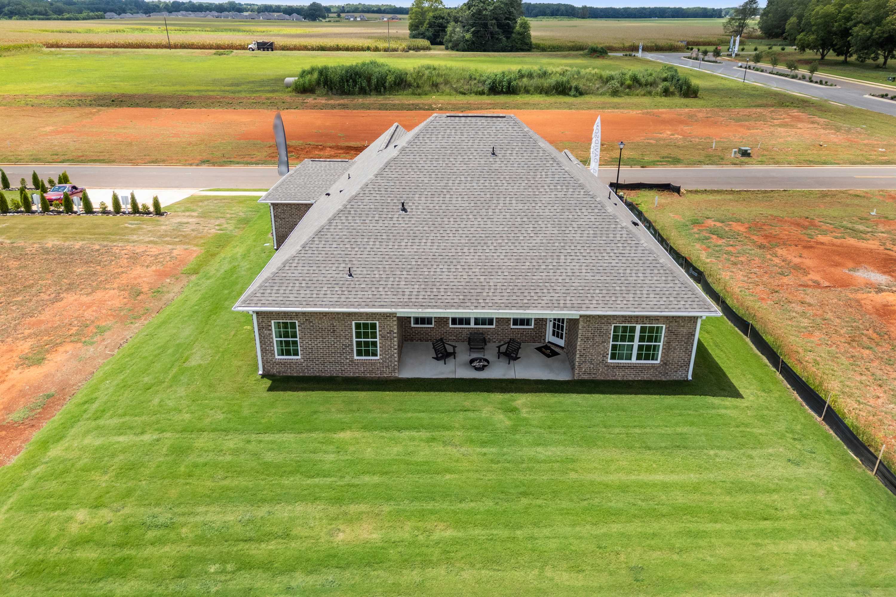 Brick ranch home at Kendall Farms in Toney Alabama with covered patio, fire pit, seating and green yard