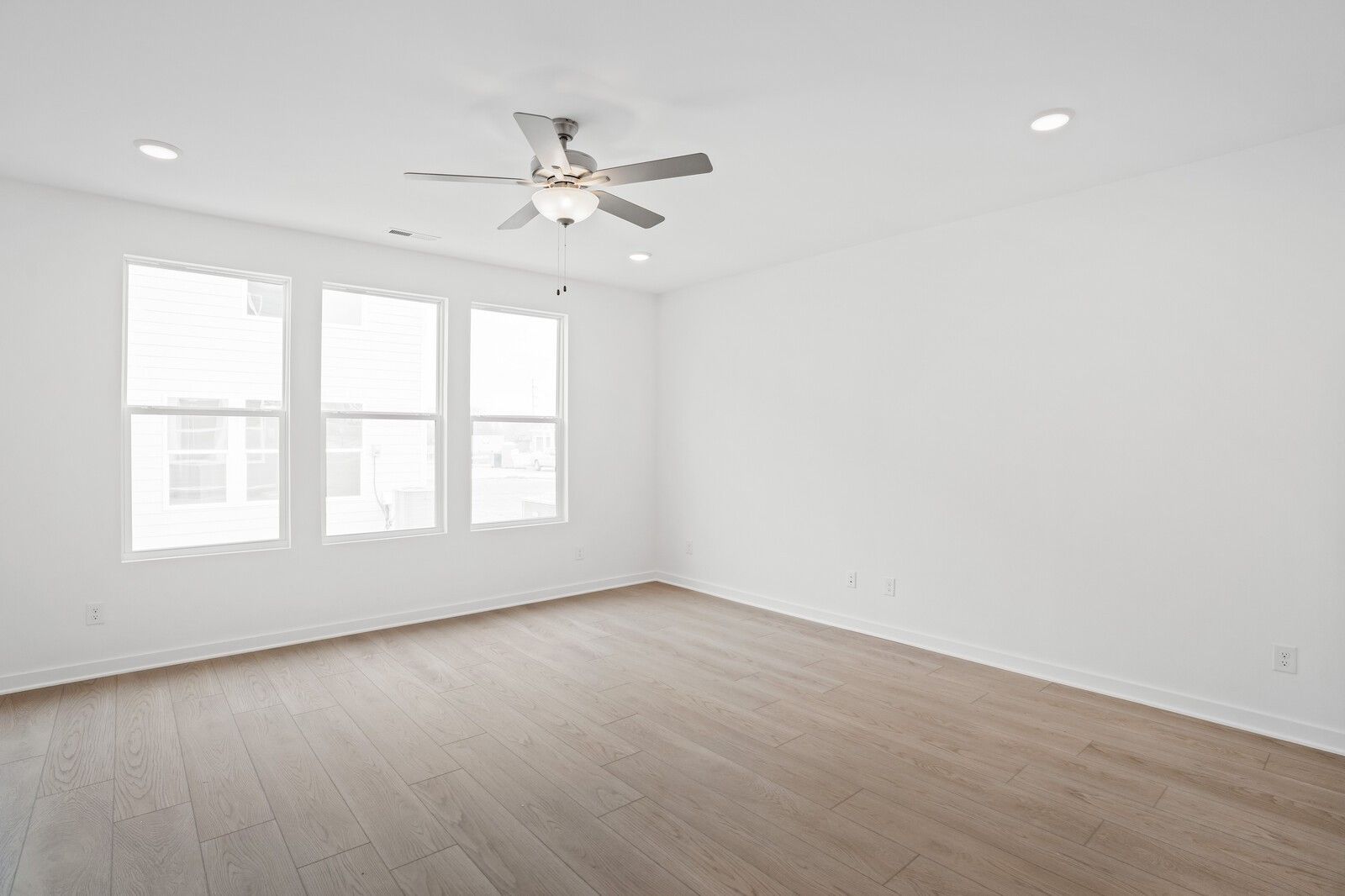 Bright bedroom with large windows, ceiling fan, recessed lights, and hardwood floors in Davidson Homes The Logan B, White House, TN