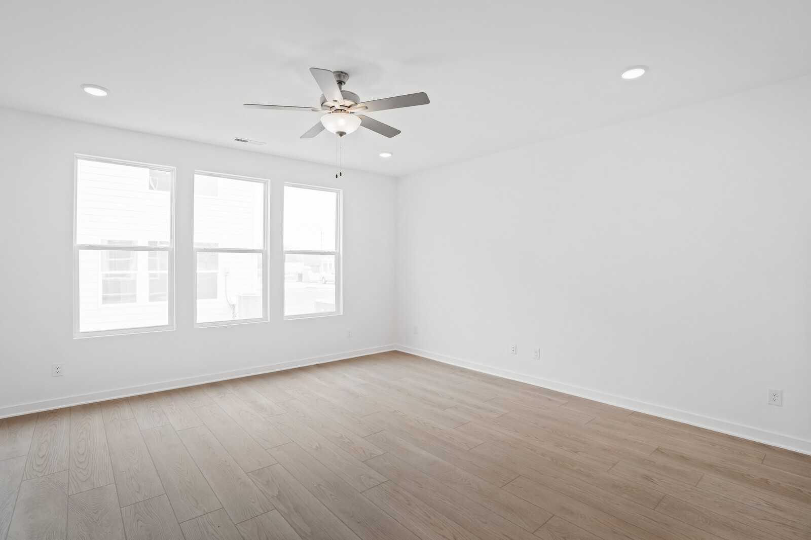 Bright bedroom with large windows, ceiling fan, recessed lights, and hardwood floors in Davidson Homes The Logan B, White House, TN
