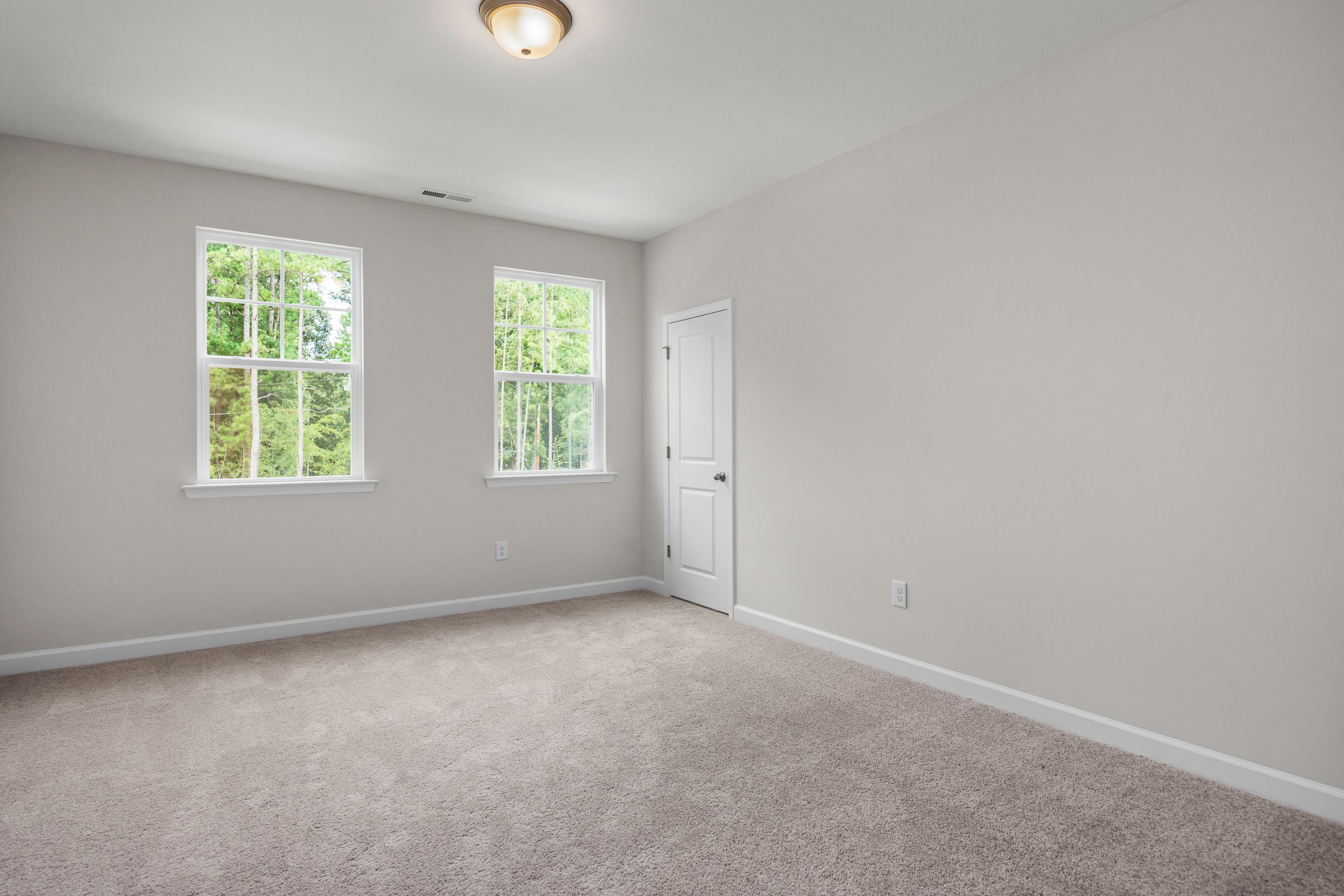 Spacious upstairs bedroom in The Aspen home featuring large windows, light gray walls, white trim, and carpeted floor