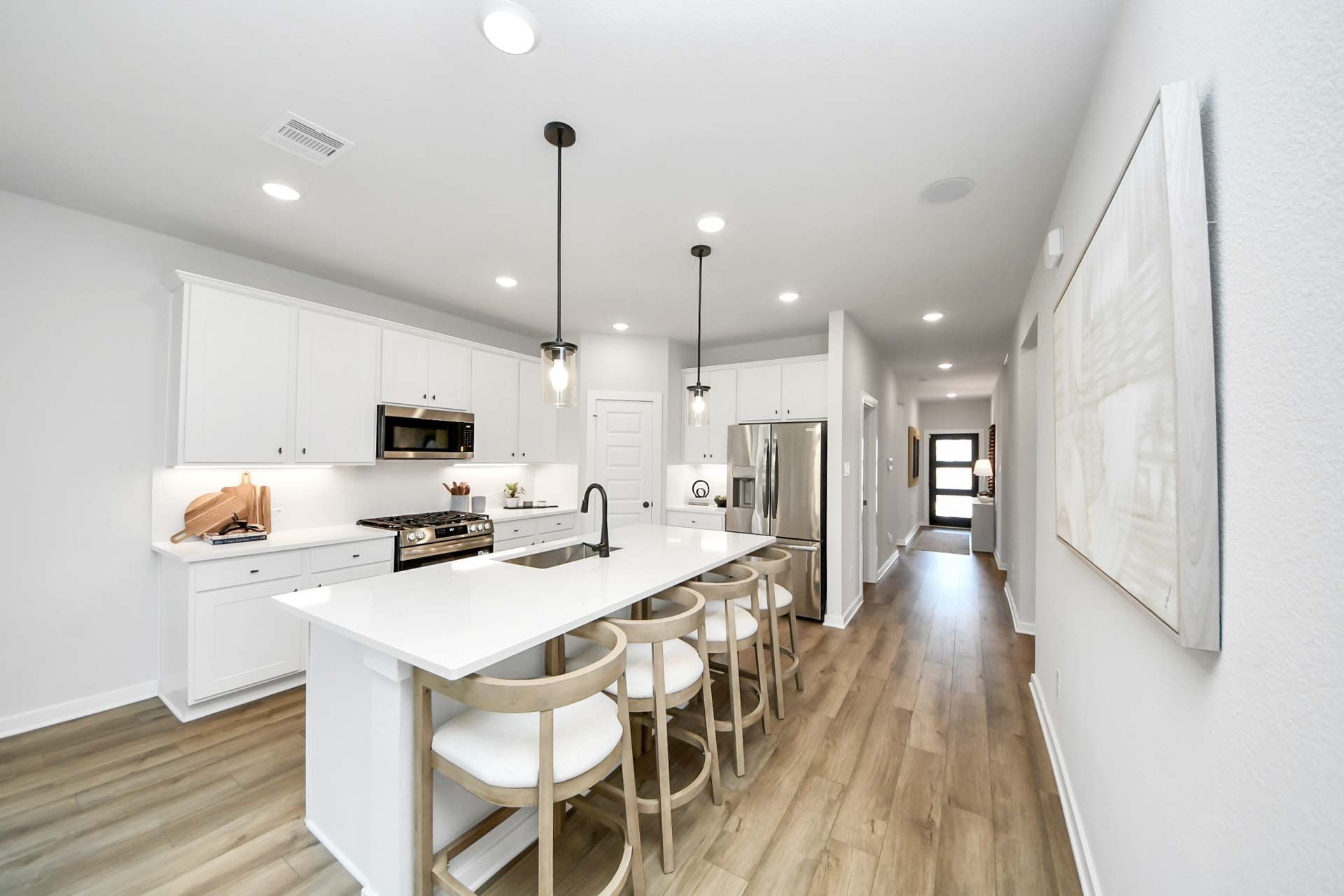 Modern kitchen with white cabinets and center island at Enclave at Newport in Crosby, TX by Davidson Homes.