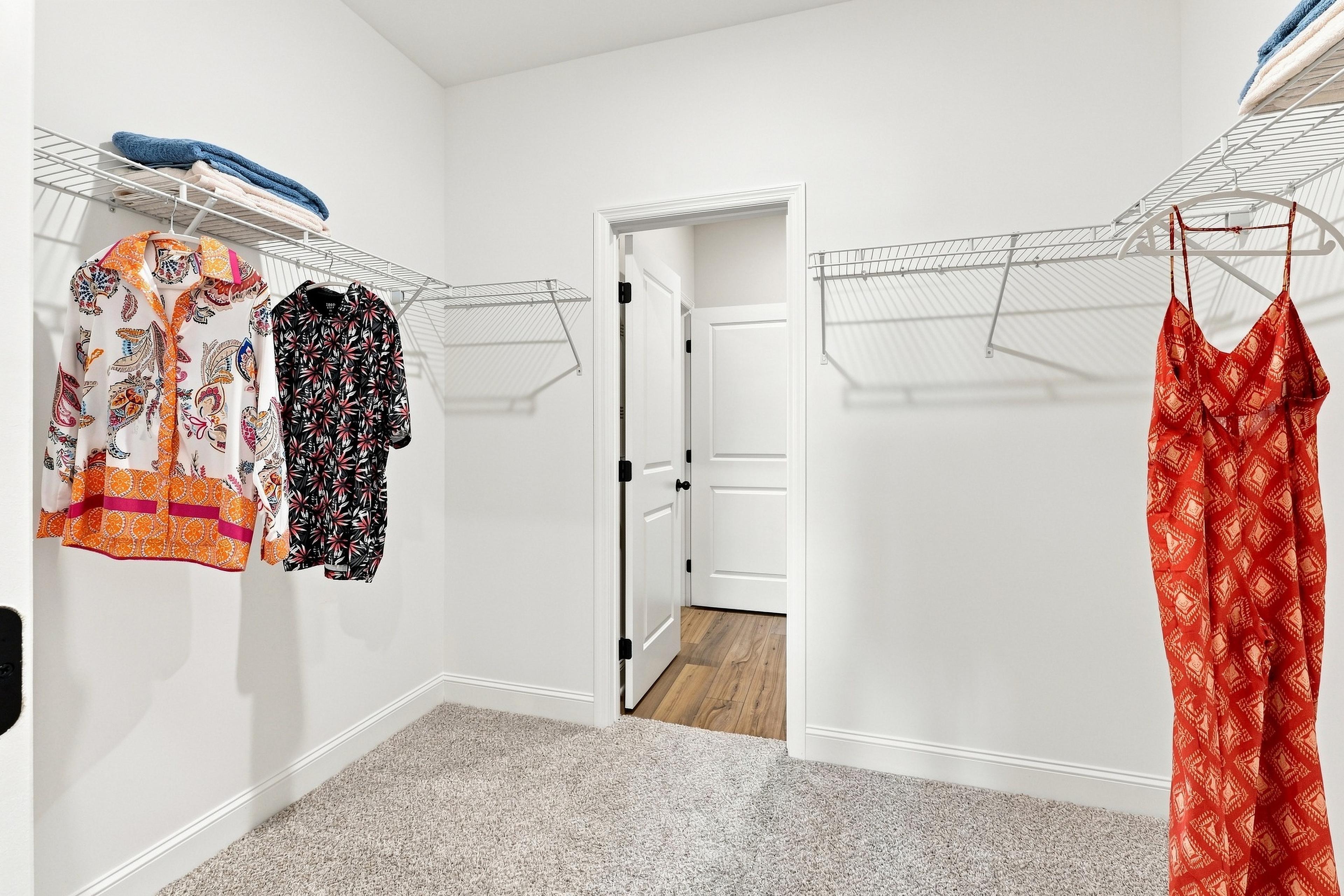 Spacious walk-in closet with wire shelving at Bailey Park by Davidson Homes in Fayetteville, TN, featuring carpet flooring