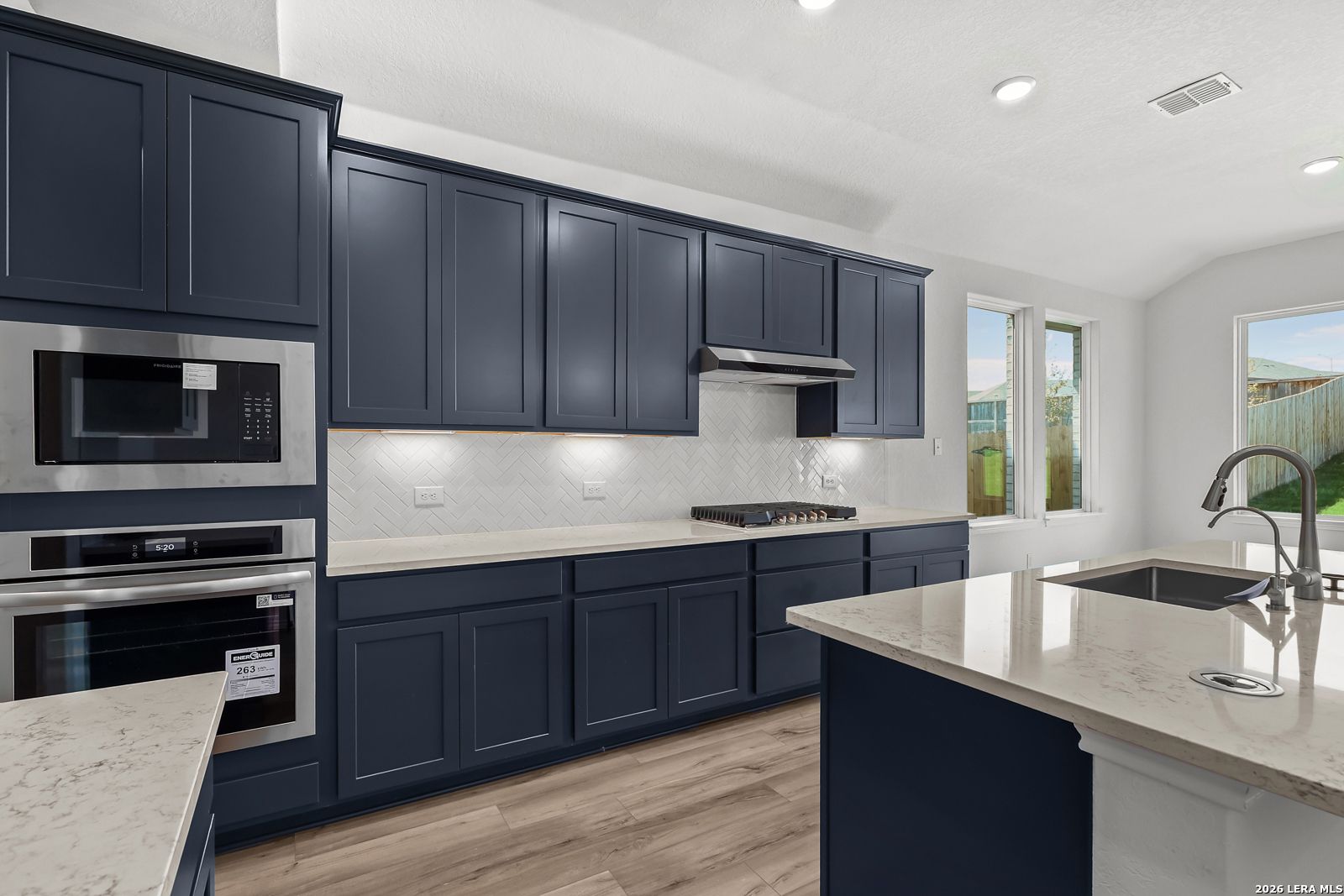 Modern navy kitchen with white quartz counters, stainless double oven, island in Davidson Homes Sequoia B, San Antonio