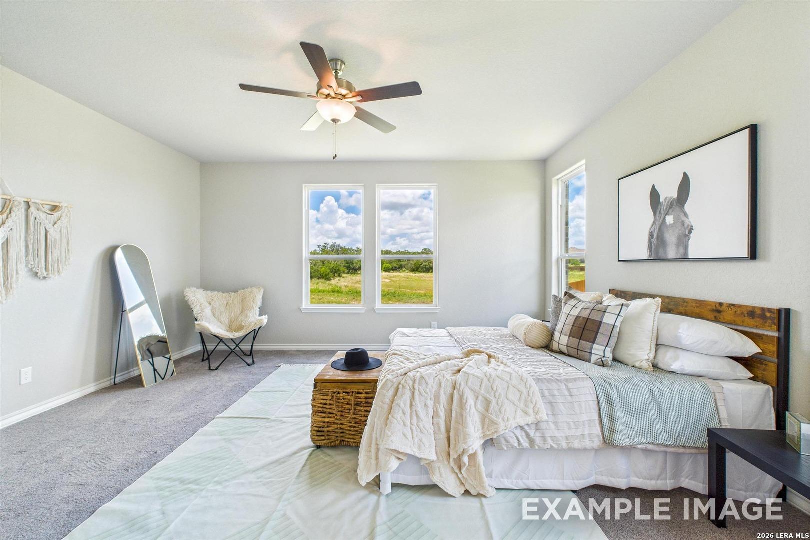 Bright, modern bedroom in The Foster F floor plan at Potranco Oaks, featuring a king bed and scenic backyard views.