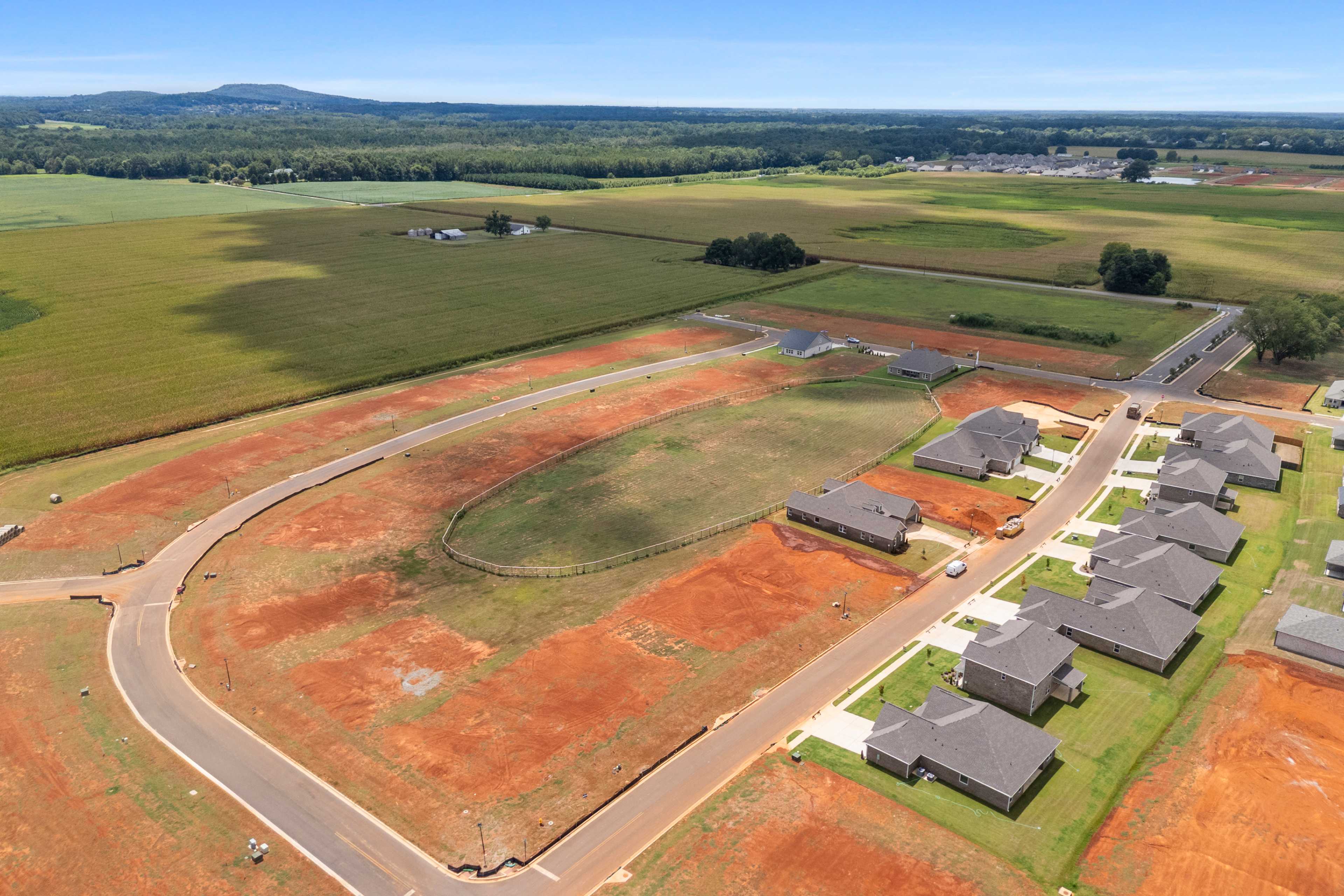 Aerial view of new construction homes at Kendall Farms in Toney Alabama by Davidson Homes with red dirt roads and surrounding fields
