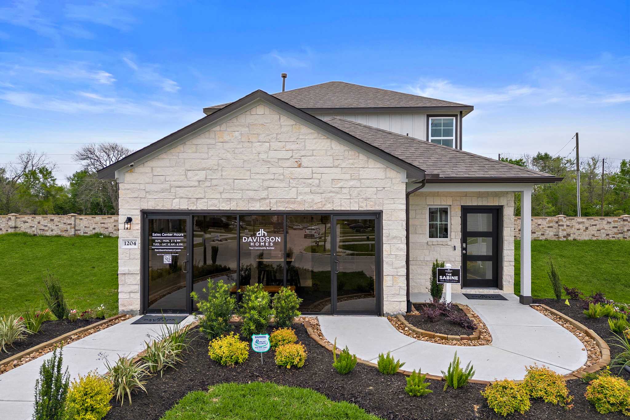 Modern stone facade home exterior at The Villages at WestPointe in Dayton Texas with attached garage and lush landscaping