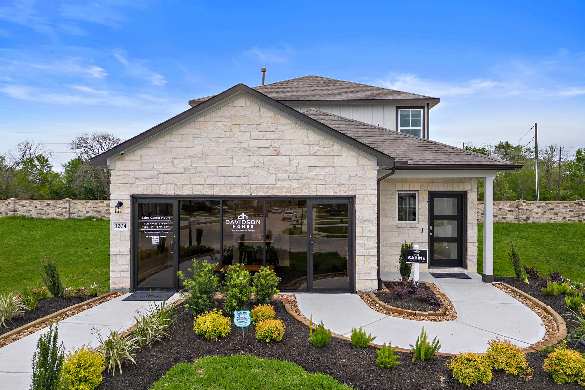 Modern stone facade home exterior at The Villages at WestPointe in Dayton Texas with attached garage and lush landscaping