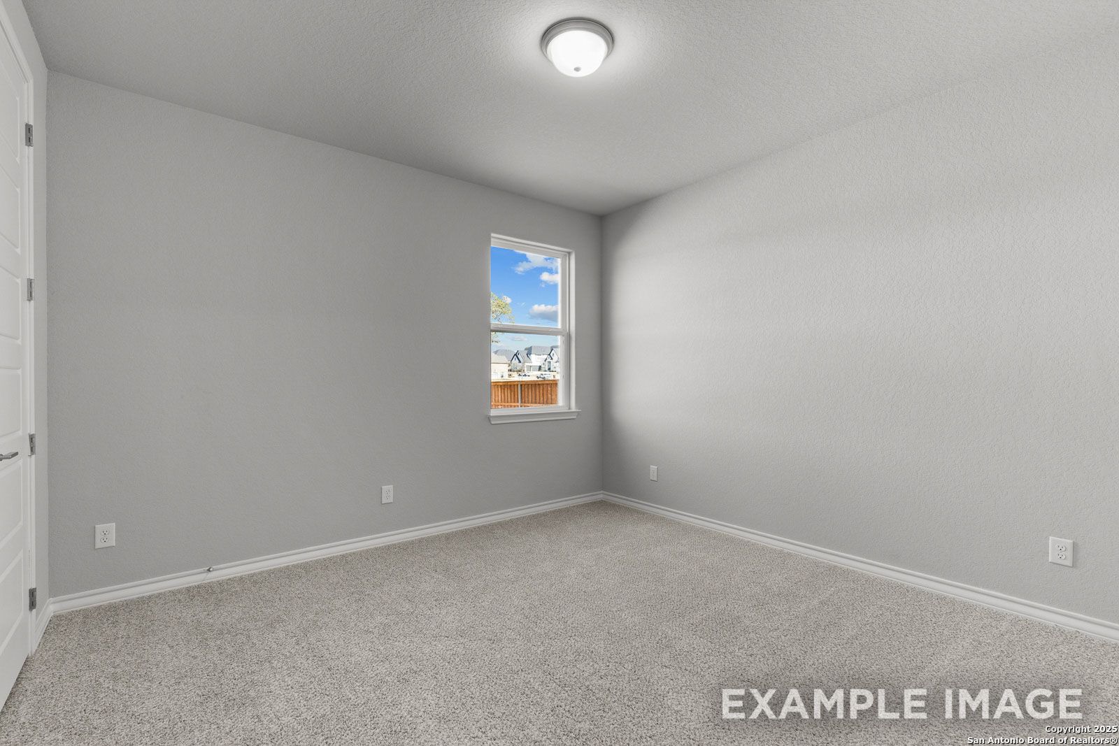 Spacious secondary bedroom in The Oxford H floor plan featuring neutral carpet, light gray walls, and natural light.