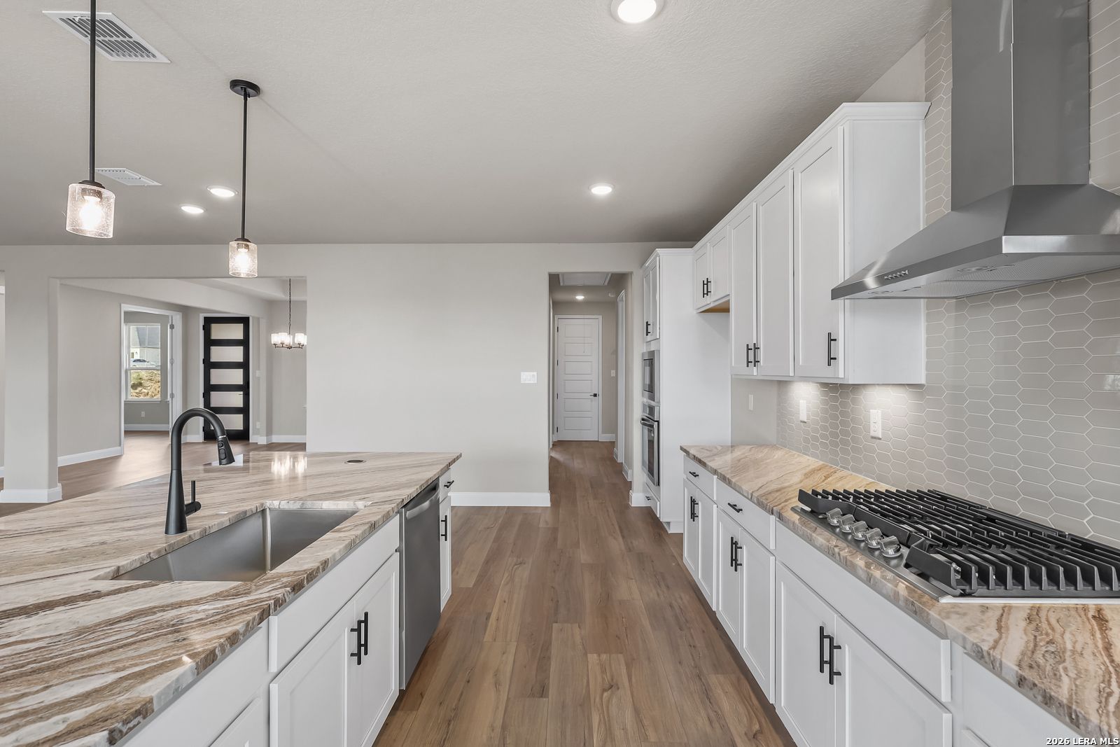 Modern kitchen with white shaker cabinets, marble island, gas cooktop, and pendant lights in The Foster E floor plan, Castroville, TX