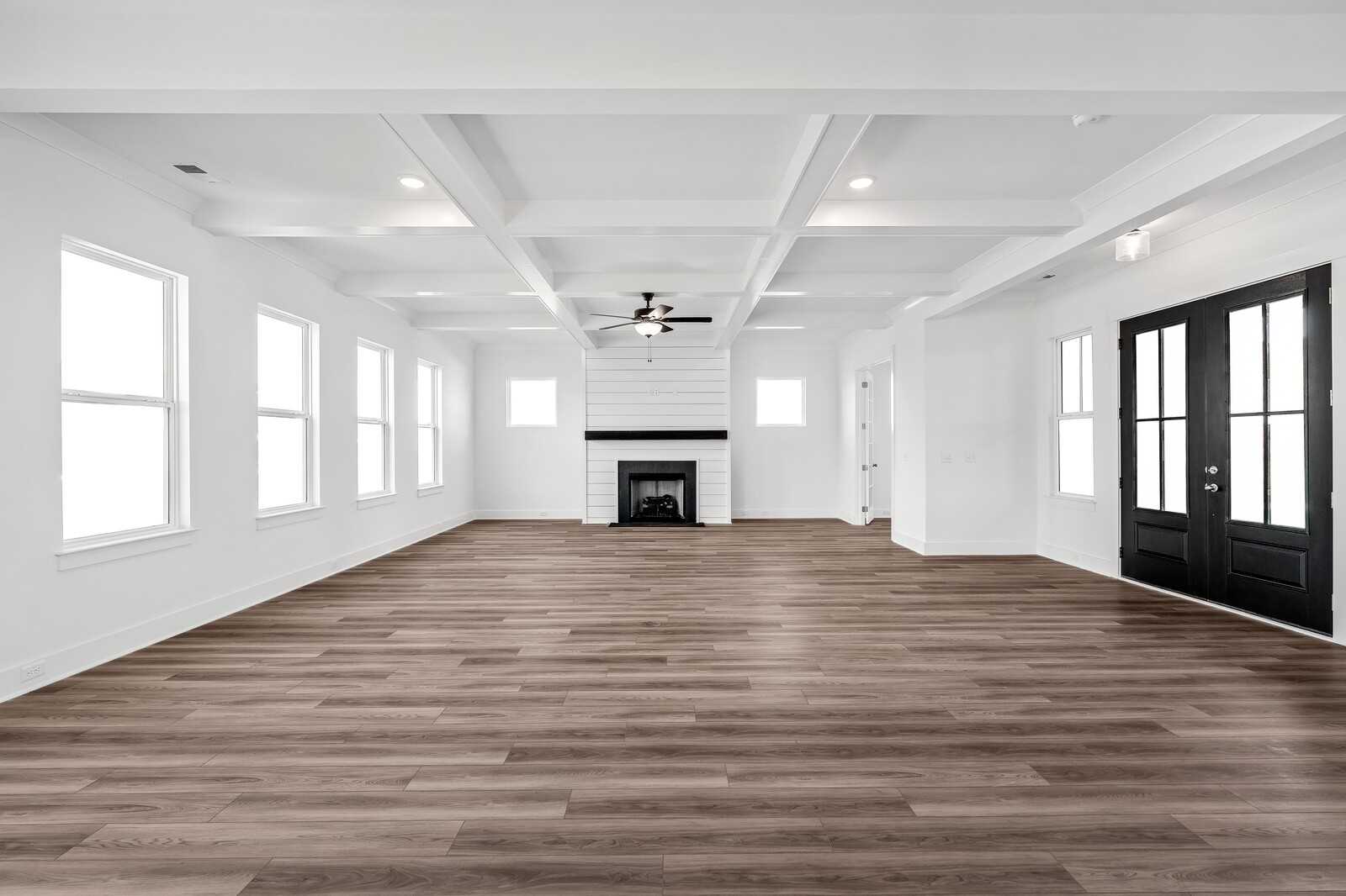 Spacious great room with modern black fireplace, hardwood floors, coffered ceiling, and large windows in Davidson Homes The Alston A, Murfreesboro