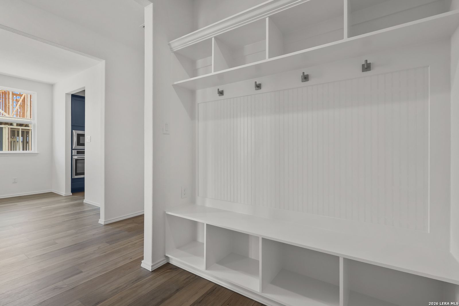 White built-in mudroom with bench, cubbies, coat hooks, and beadboard walls in Davidson Homes The Glenwood E, Elmendorf, Texas