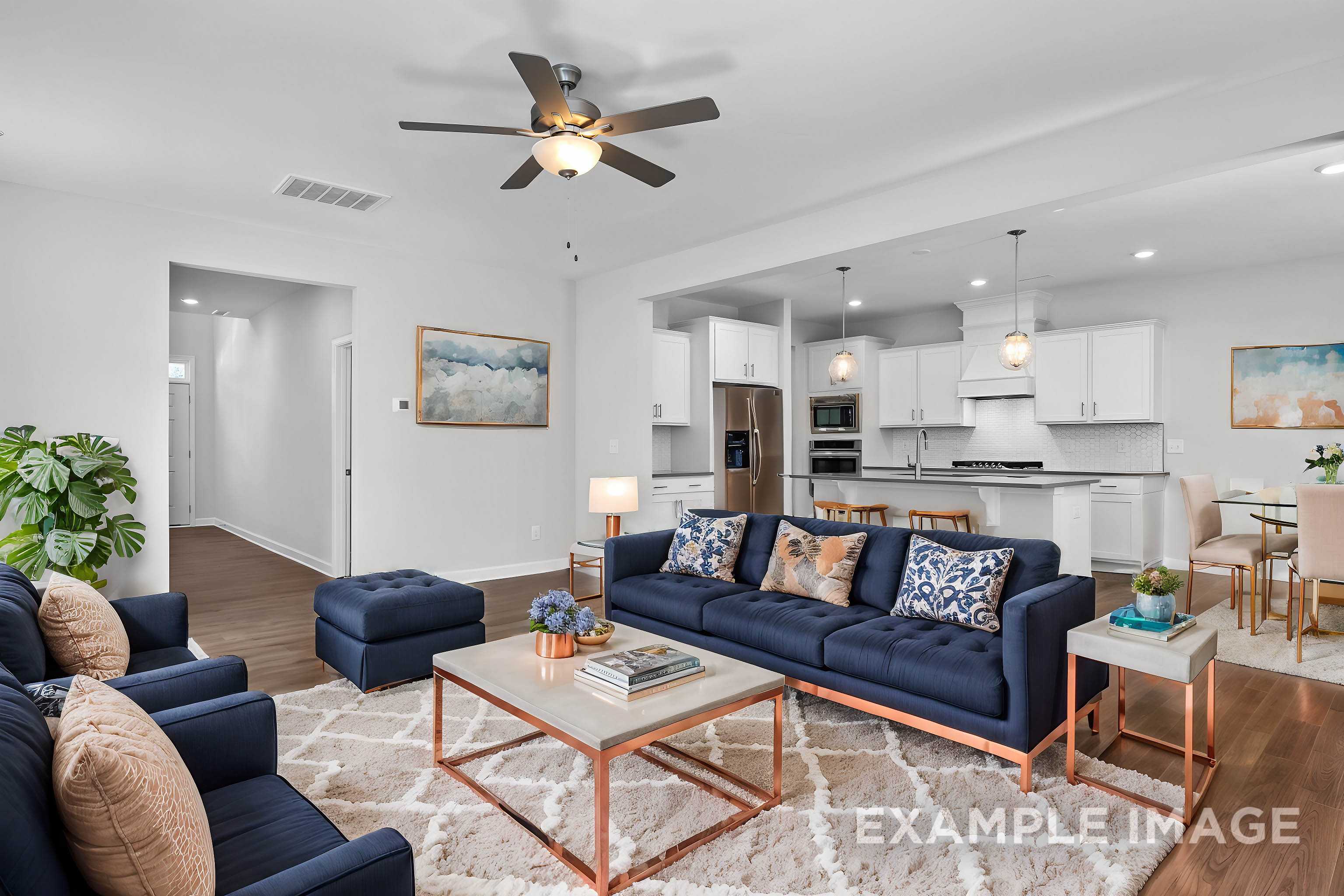 Spacious open-concept living room in The Gavin C with navy sectional sofa, coffee table, ceiling fan, and dining nook