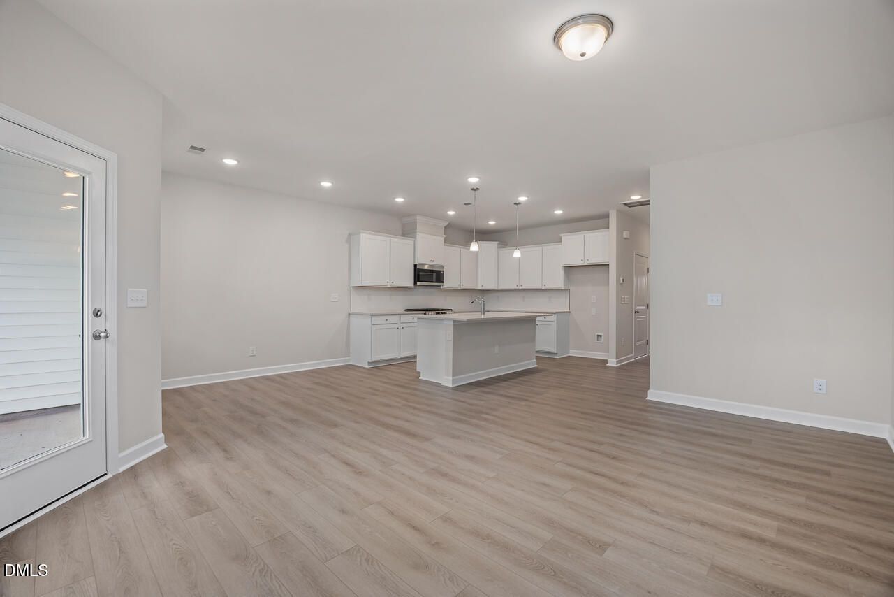 Modern open-concept kitchen with white cabinets, large island, and stainless appliances in The Graham floor plan, Fuquay-Varina, NC