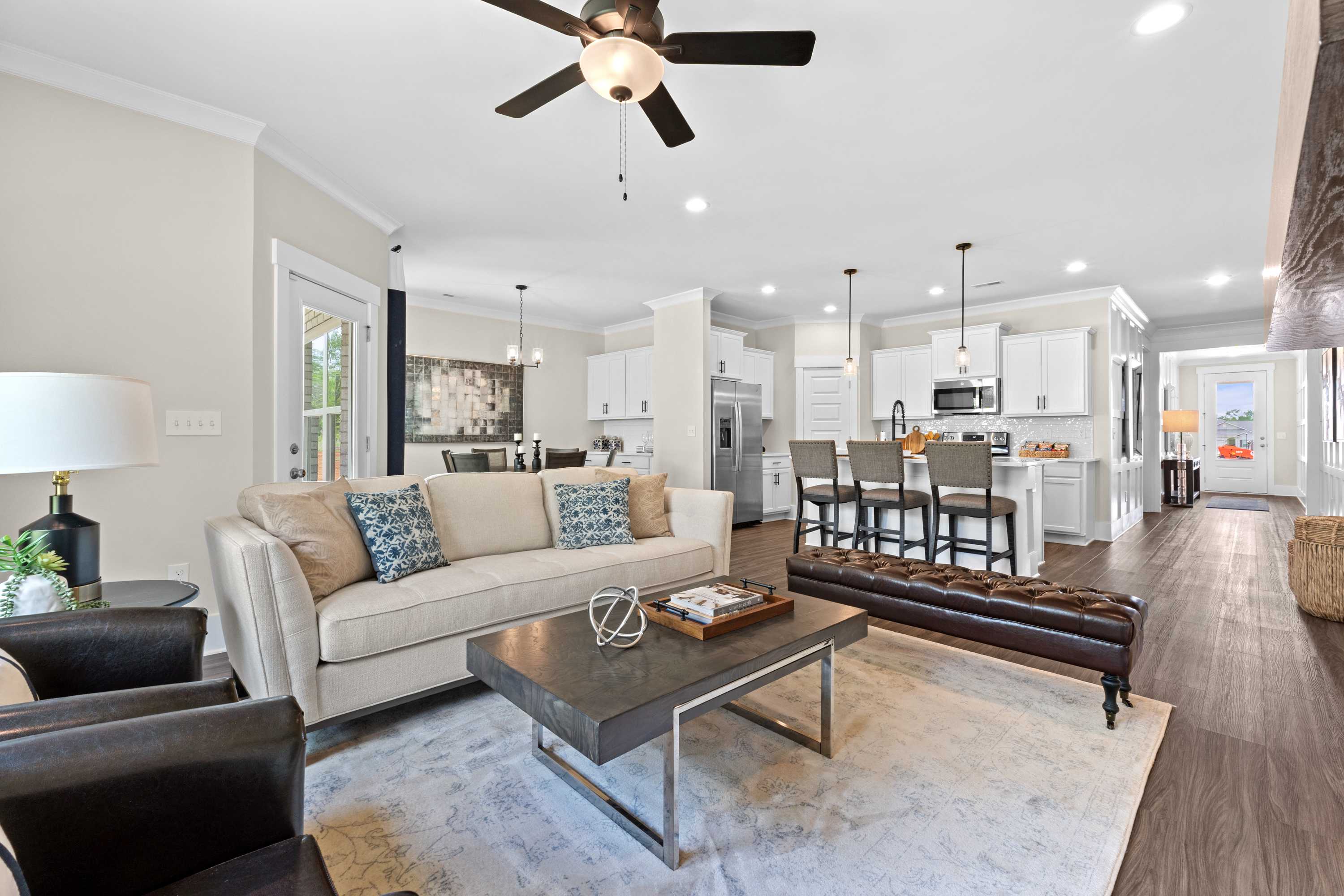Spacious open-concept living room in Ivy Hills, Toney Alabama with beige sofa, hardwood floors, ceiling fan and white kitchen island