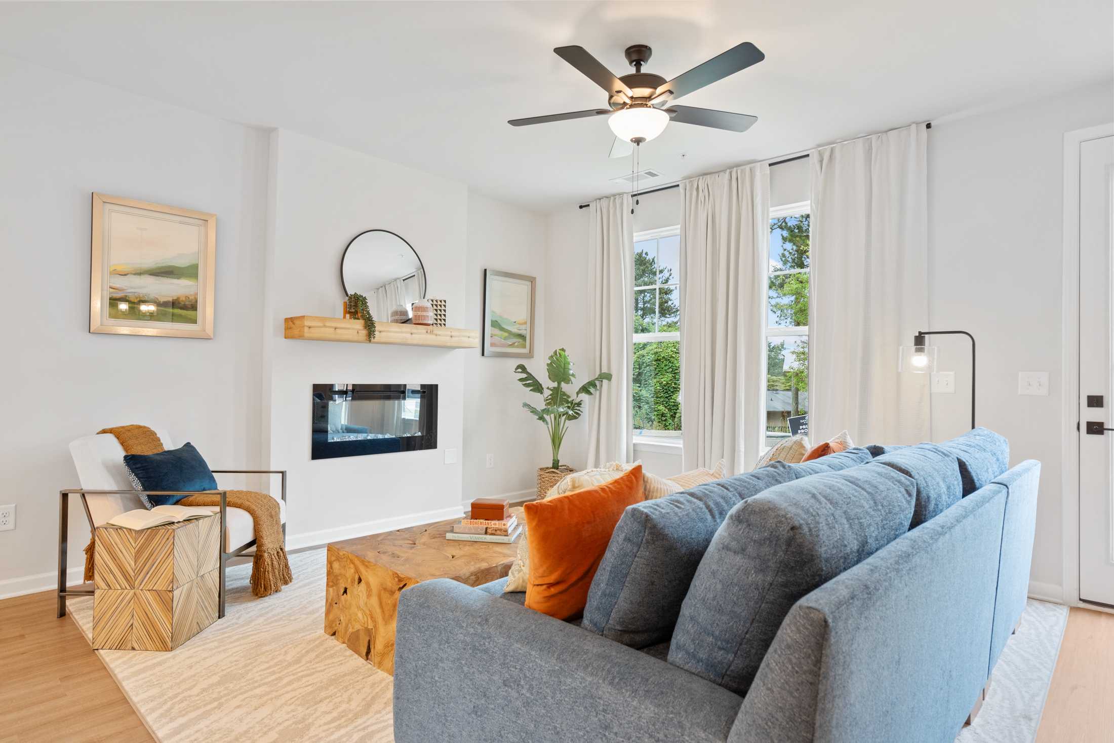 Cozy living room at Rosehill Townhomes in Marietta GA with blue sectional sofa, fireplace, wooden coffee table, and large windows
