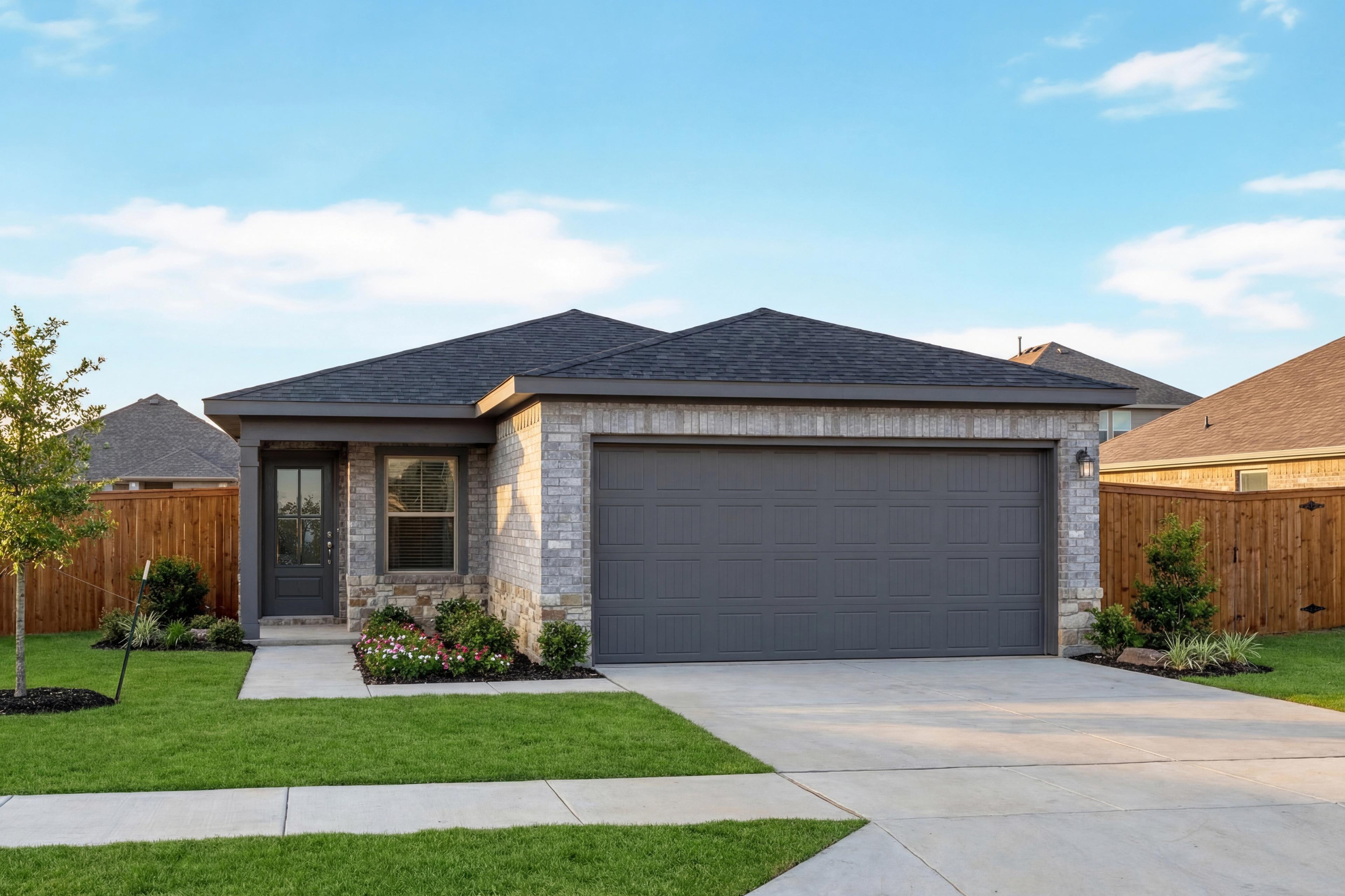 Modern single-story facade of The Colorado G with stone and gray siding, 2-car garage, landscaped yard in Heartland Texas