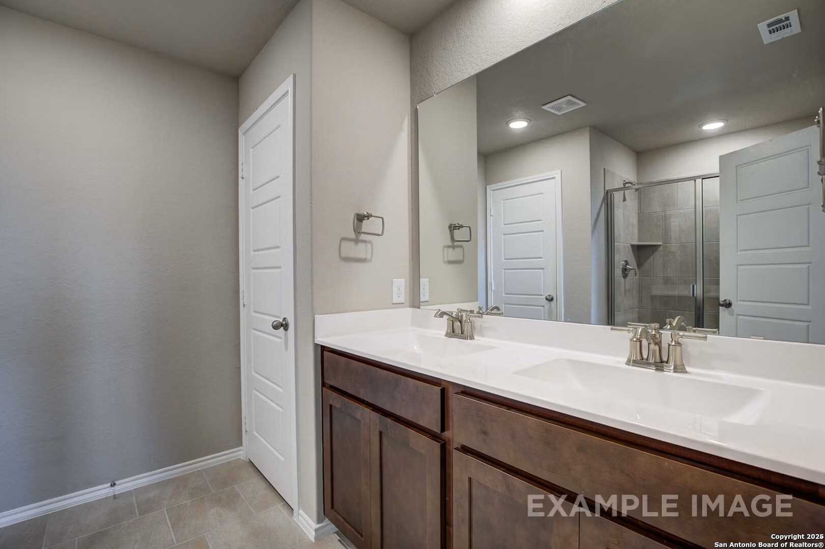 Modern master bathroom featuring double vanity, walk-in shower, and frameless mirror in Davidson Homes The Murray K, San Antonio