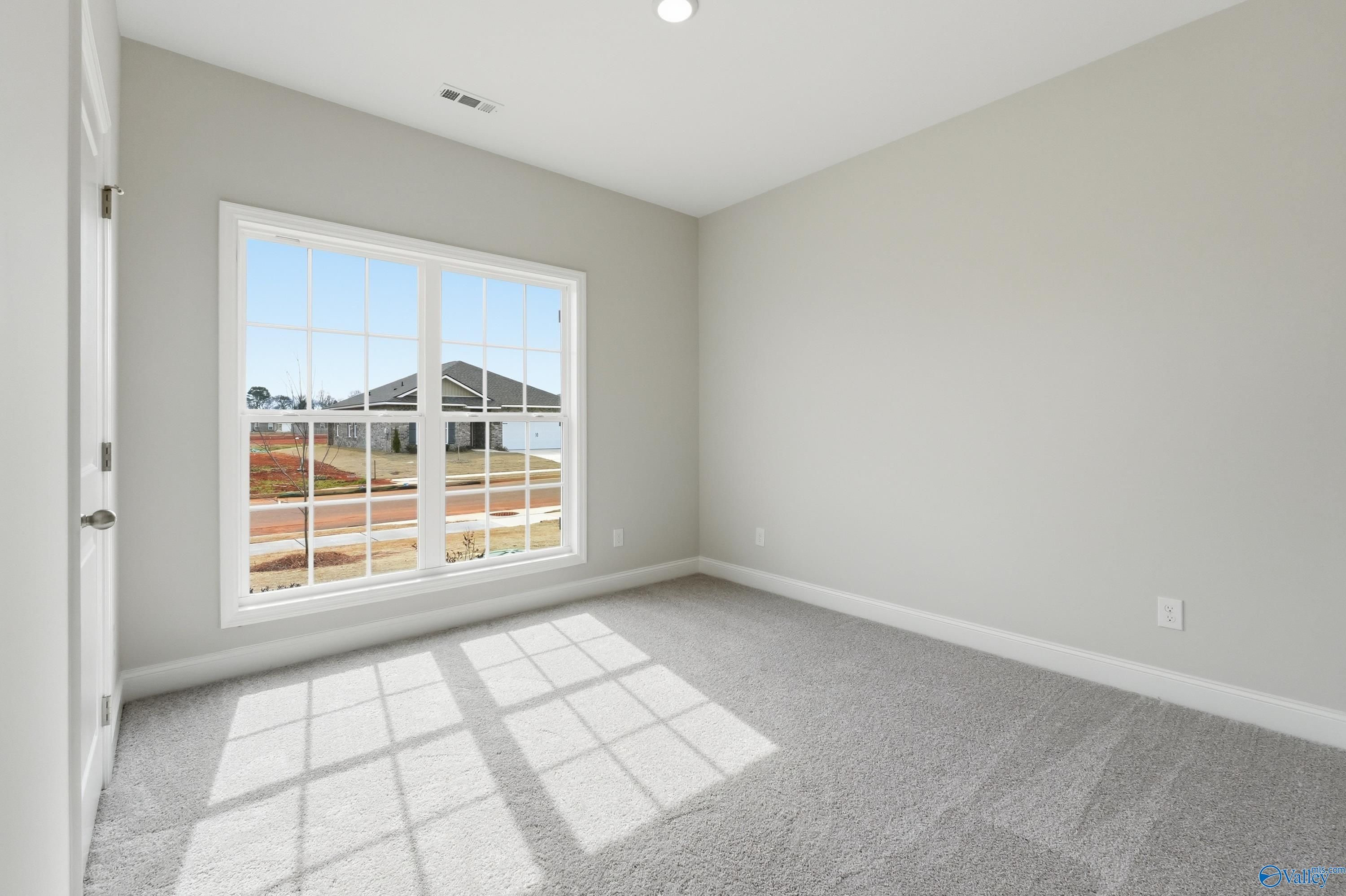 Bright empty bedroom with large sunny window overlooking neighborhood in Davidson Homes The Franklin, Meridianville, Alabama