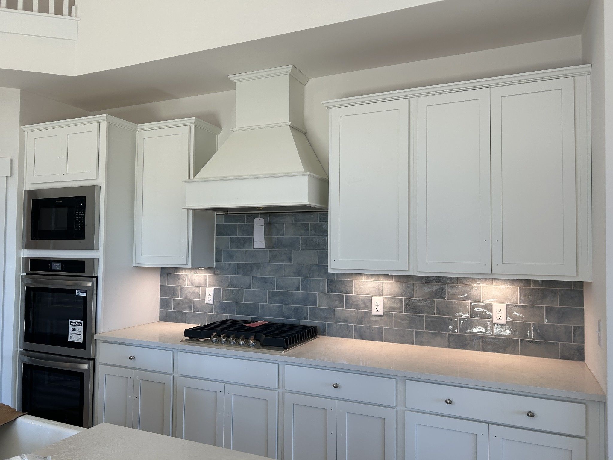 Modern white kitchen featuring blue subway tile backsplash, stainless steel appliances, and spacious island in The Ridgeport D, Mt. Juliet, TN