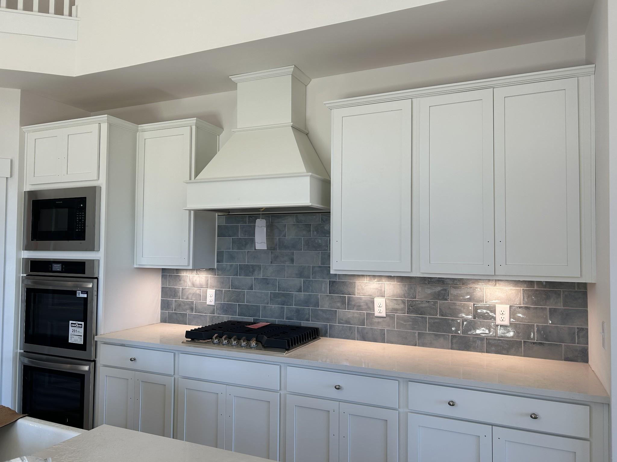 Modern white kitchen featuring blue subway tile backsplash, stainless steel appliances, and spacious island in The Ridgeport D, Mt. Juliet, TN