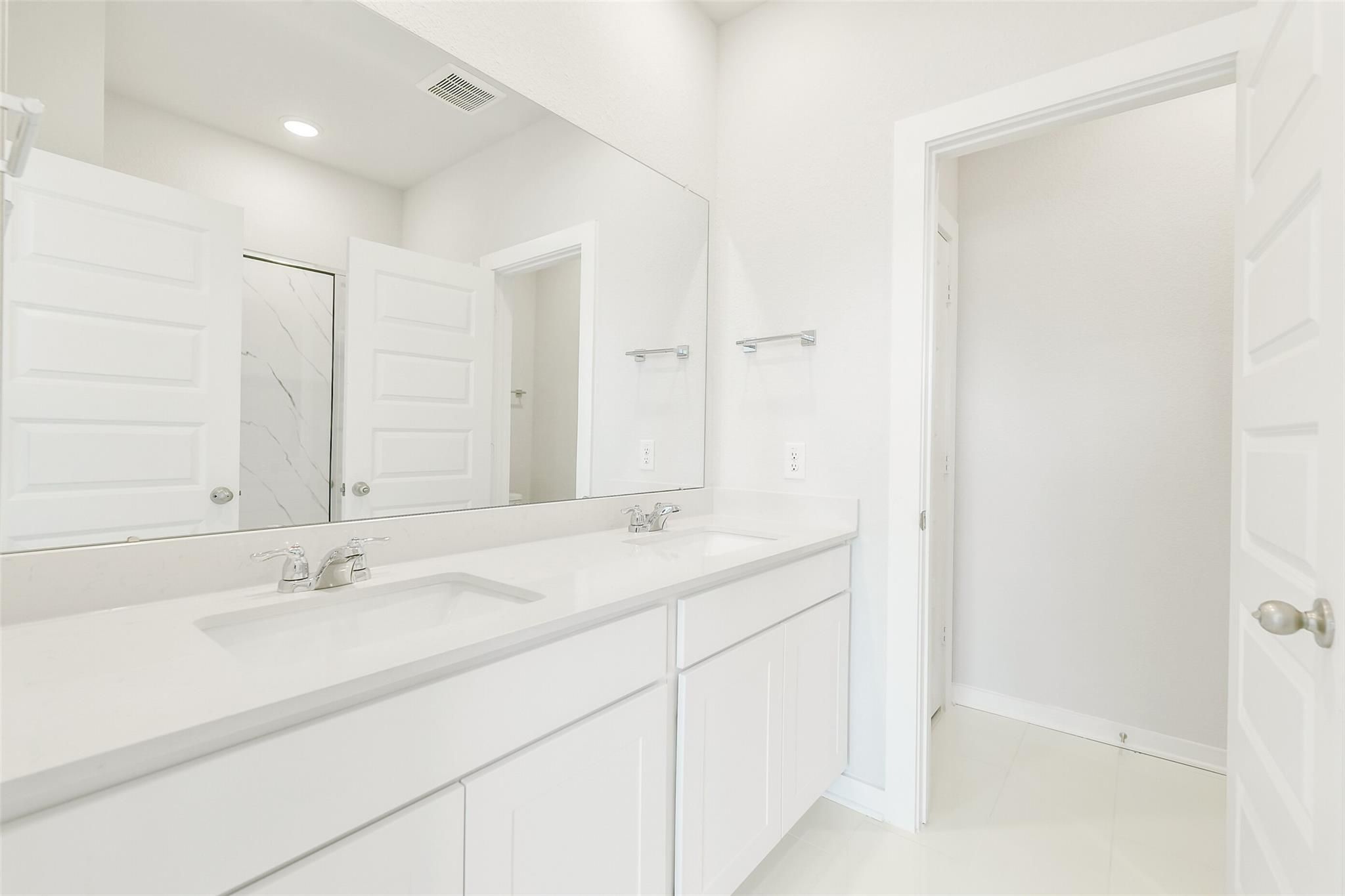 Modern master bathroom with double white vanity, quartz counters, and large mirror in Davidson Homes San Marcos E, Cleveland TX