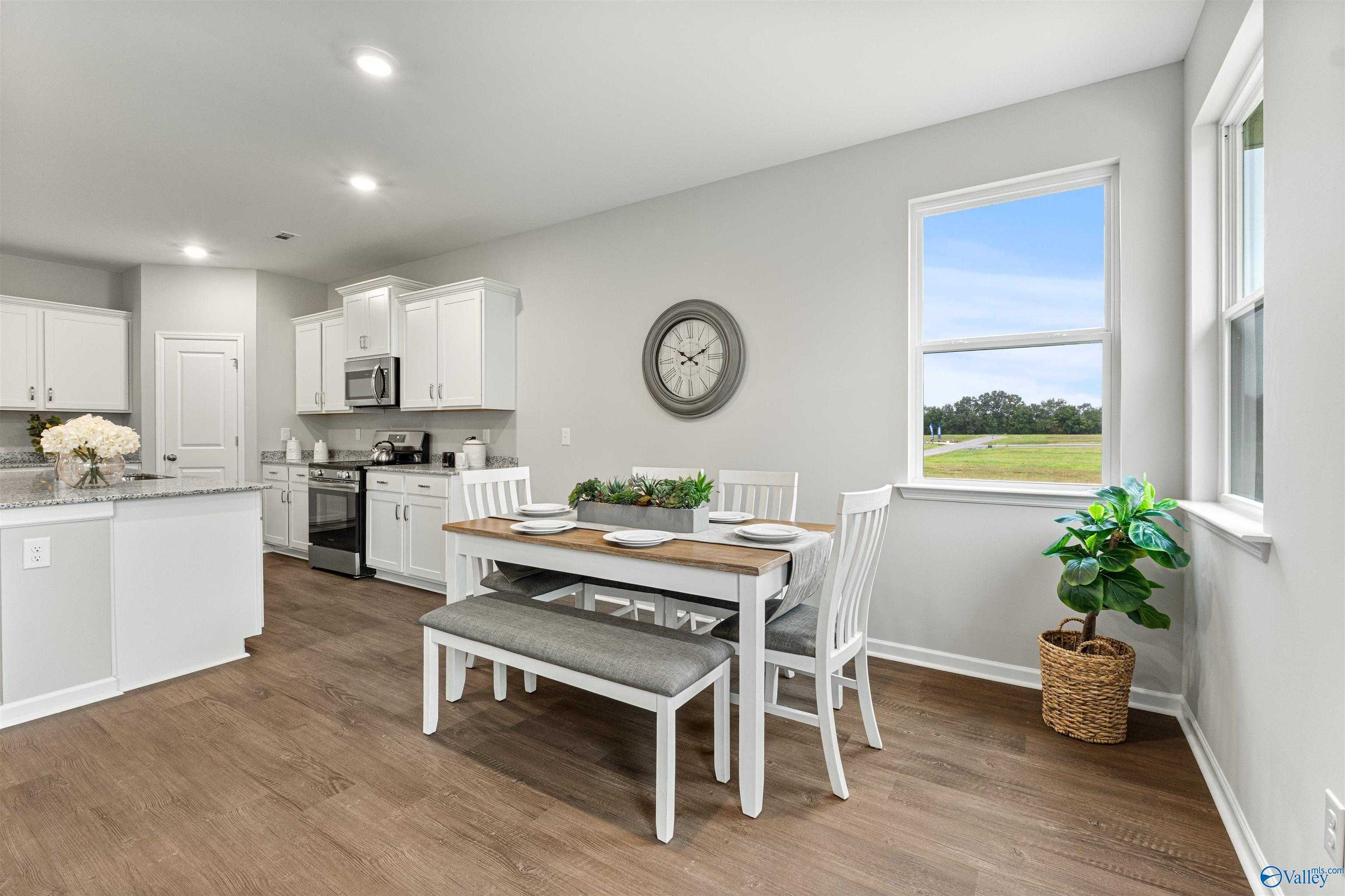 Bright dining nook with wooden table, white chairs, and kitchen view of green field in Davidson Homes The Phoenix, Fayetteville, TN