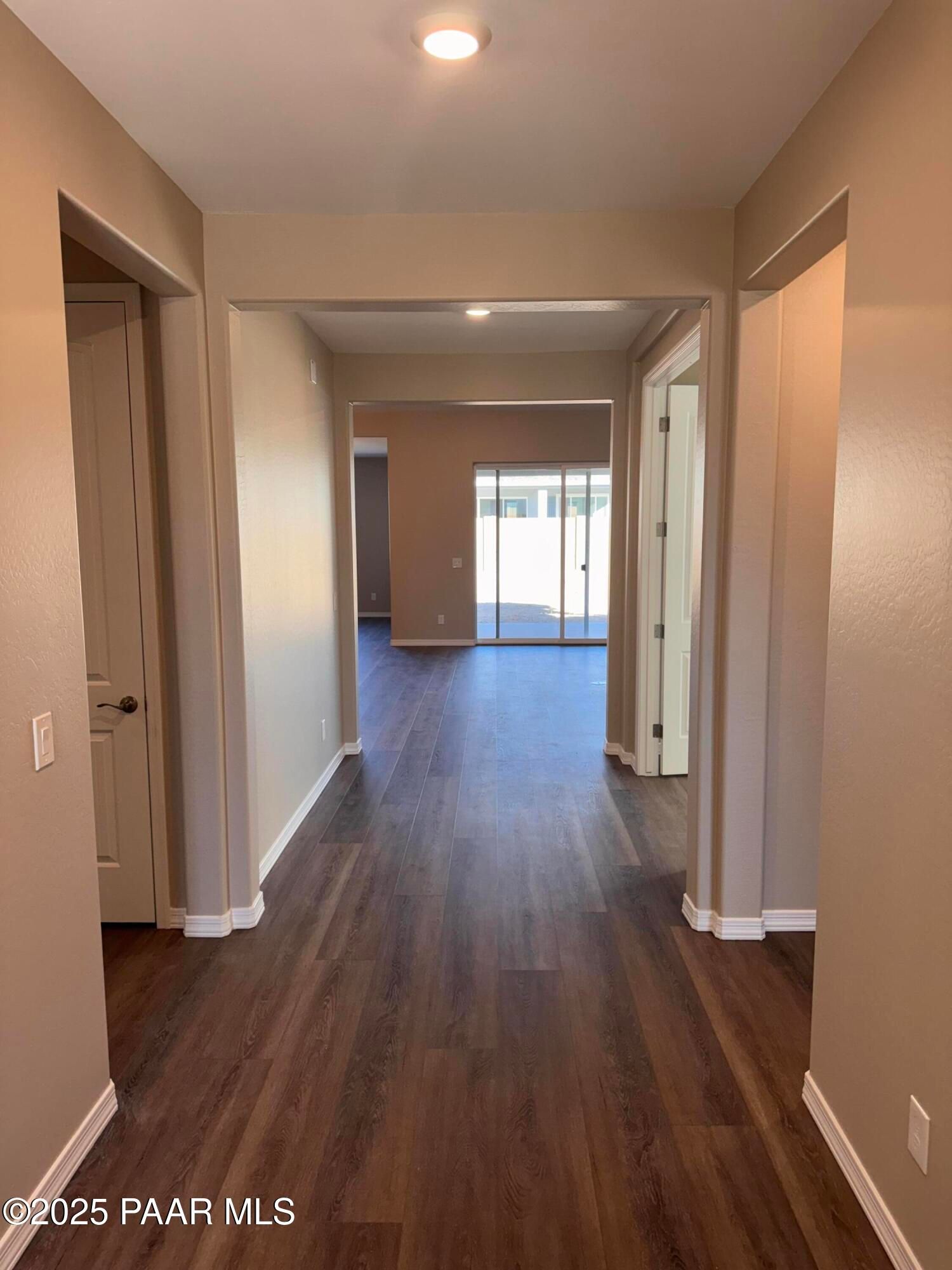 Spacious hallway with dark wood floors, beige walls, and archways to rooms in Davidson Homes Sunrise II A, Westwood, Prescott, Arizona