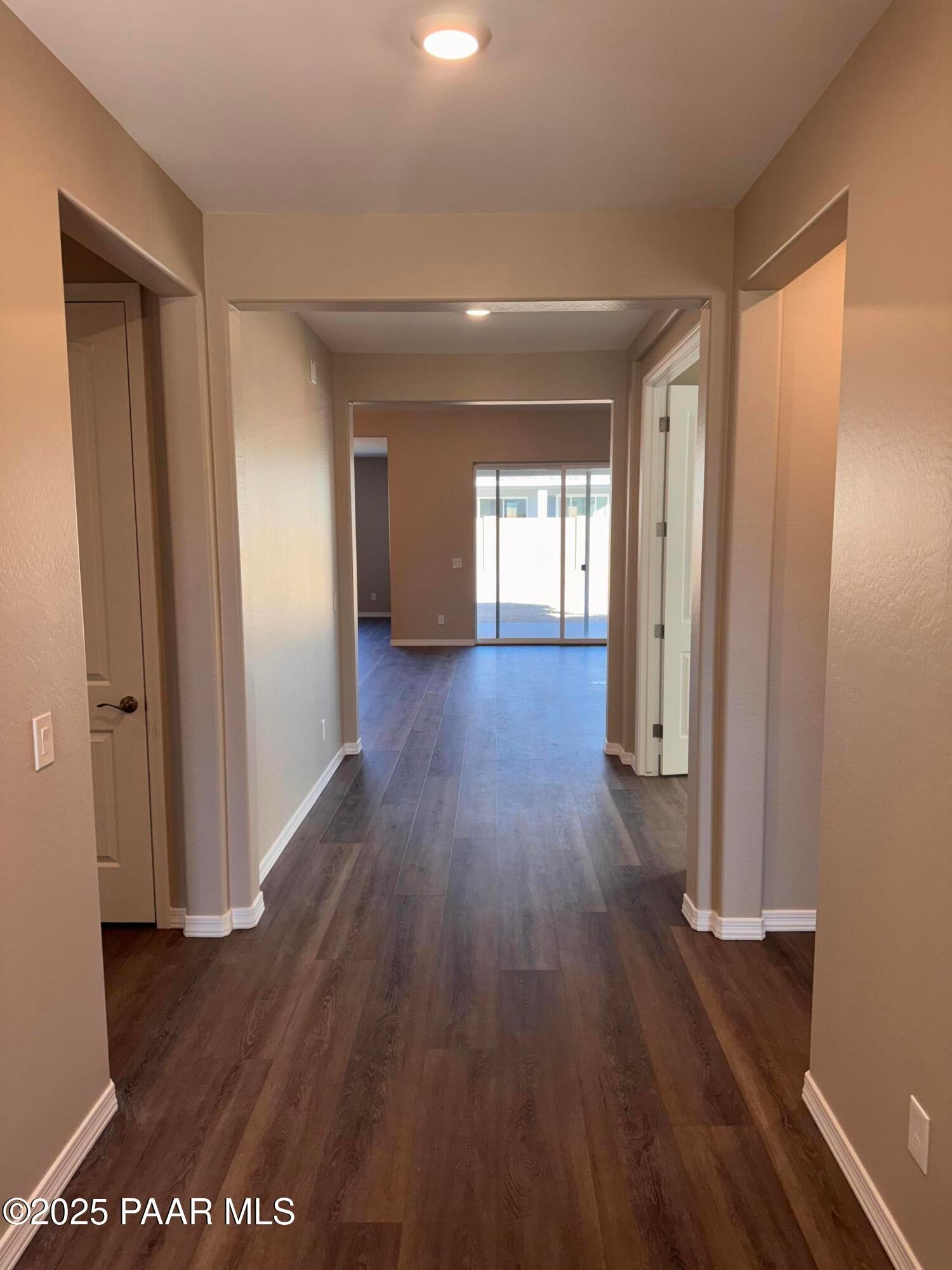 Spacious hallway with dark wood floors, beige walls, and archways to rooms in Davidson Homes Sunrise II A, Westwood, Prescott, Arizona