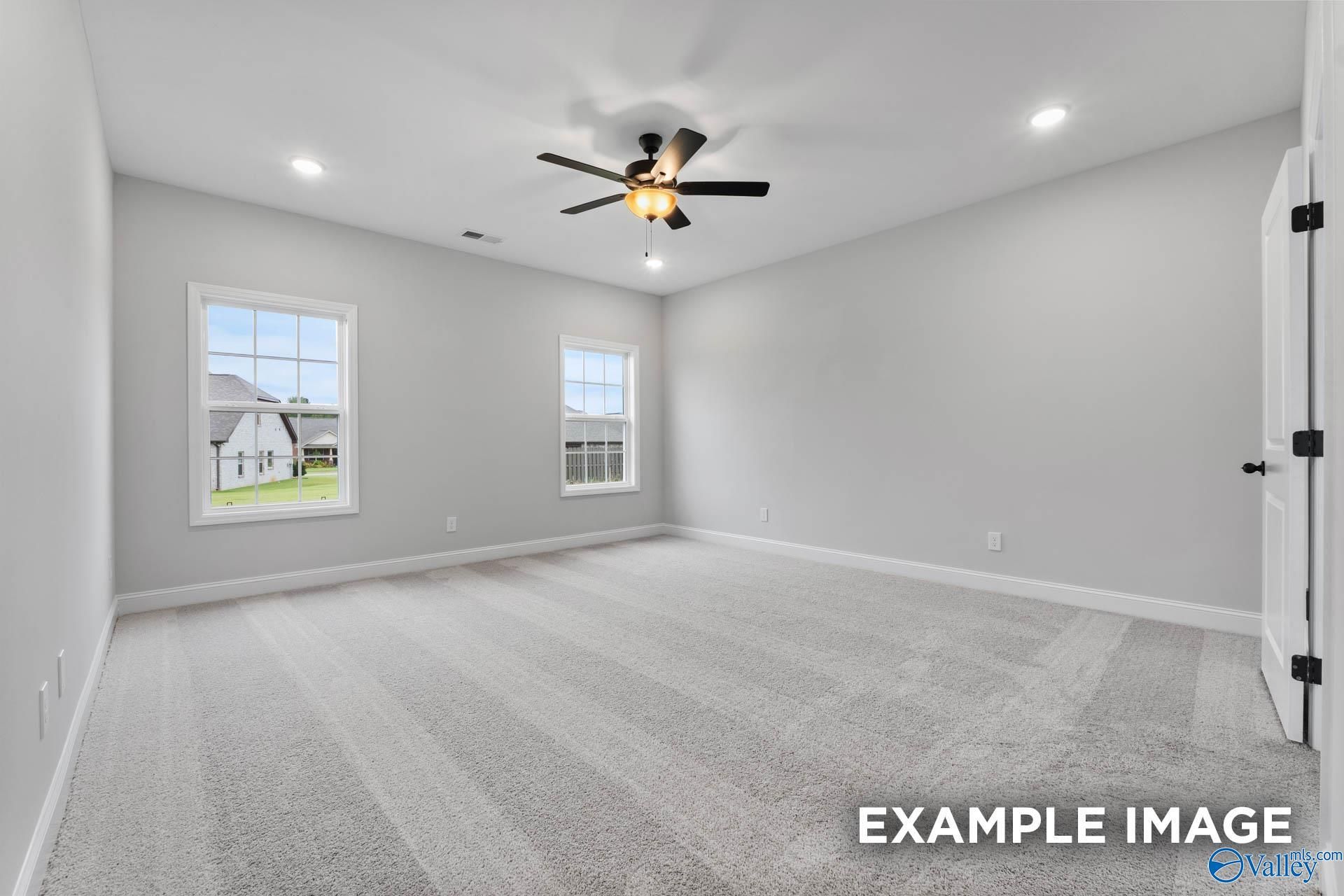 Spacious empty bedroom with light gray walls, double windows overlooking lawn, ceiling fan in Davidson Homes The Rockford, Decatur, Alabama