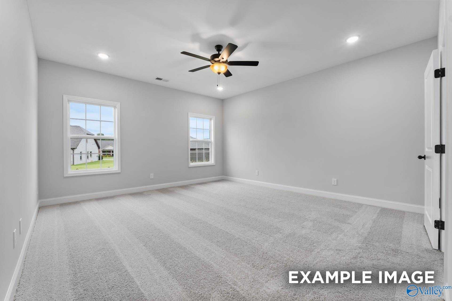 Spacious empty bedroom with light gray walls, double windows overlooking lawn, ceiling fan in Davidson Homes The Rockford, Decatur, Alabama