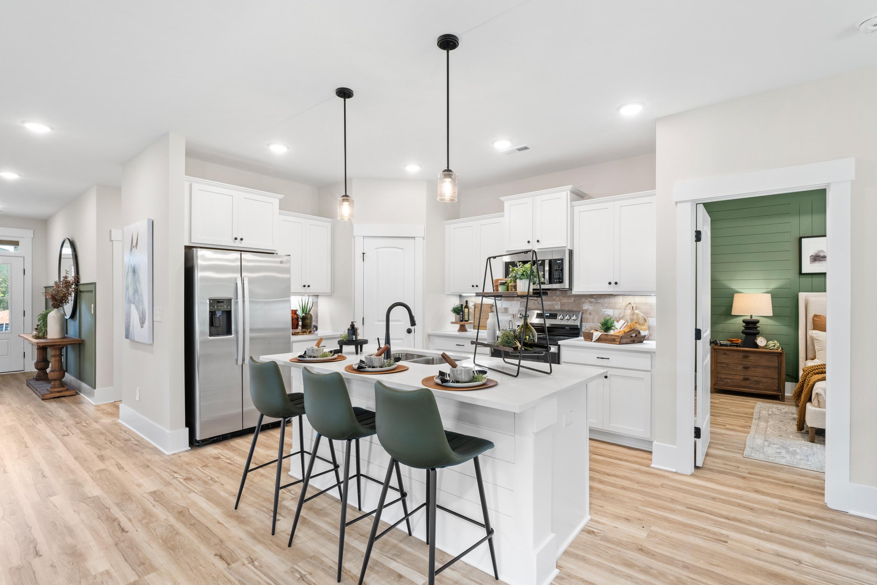 Modern kitchen at Spragins Cove in Huntsville AL with white island, green bar stools, stainless appliances, and hardwood floors
