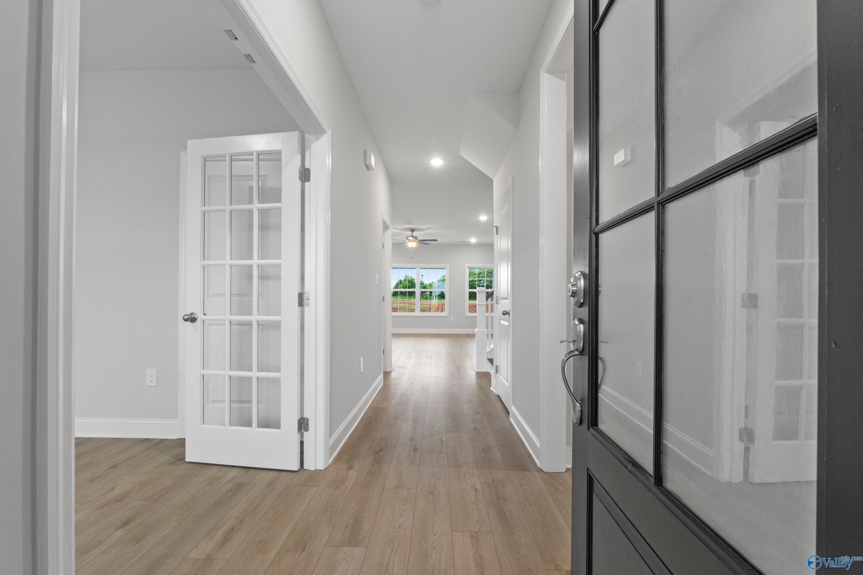 Bright entry hallway with hardwood floors, French doors, and black glass front door in Davidson Homes The Rockford B, Toney, Alabama