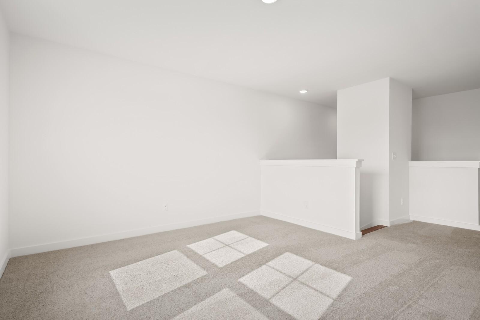 Bright upstairs hallway with white walls, staircase railing, and beige carpet in The Logan C, Gallatin, Tennessee