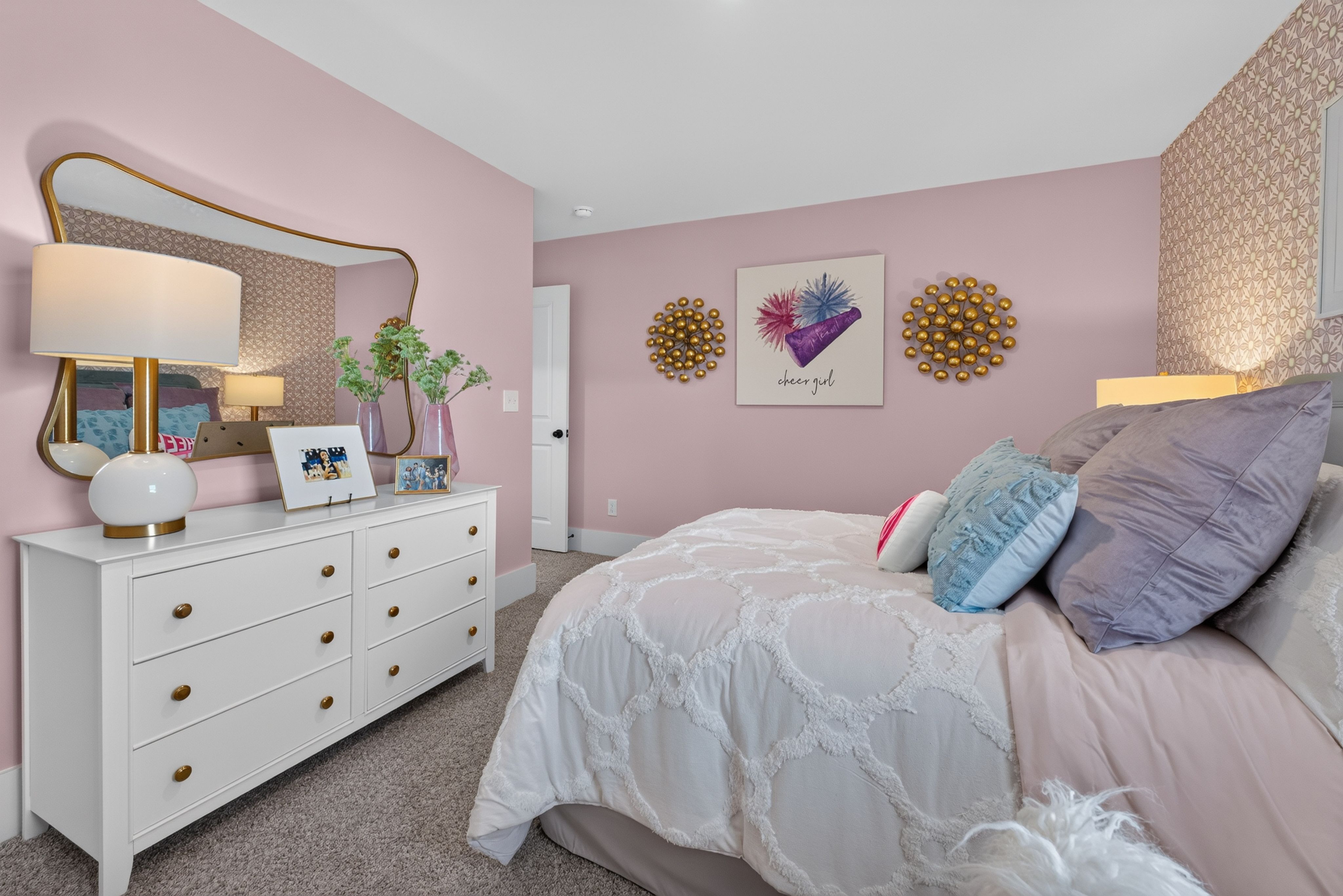 Pink bedroom interior at Evergreen Mill in Madison, Alabama by Davidson Homes with white dresser and gold accents