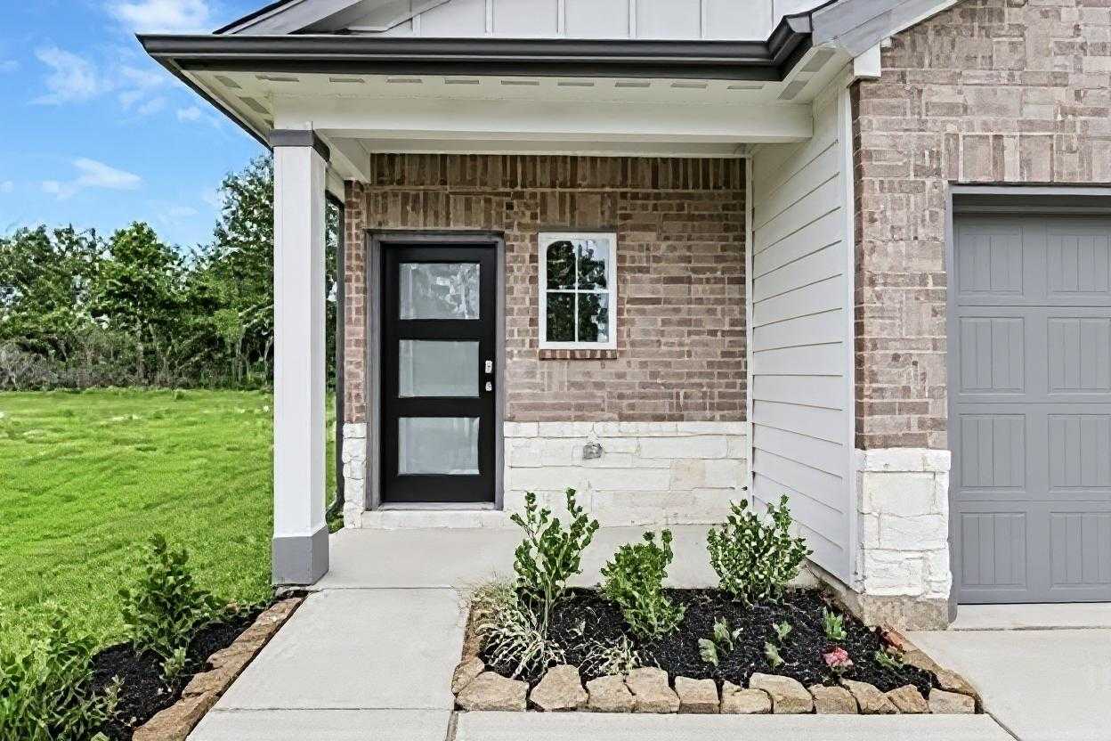 Modern brick facade with black glass door, window, and 2-car garage on The Frio G home by Davidson Homes in Conroe, Texas