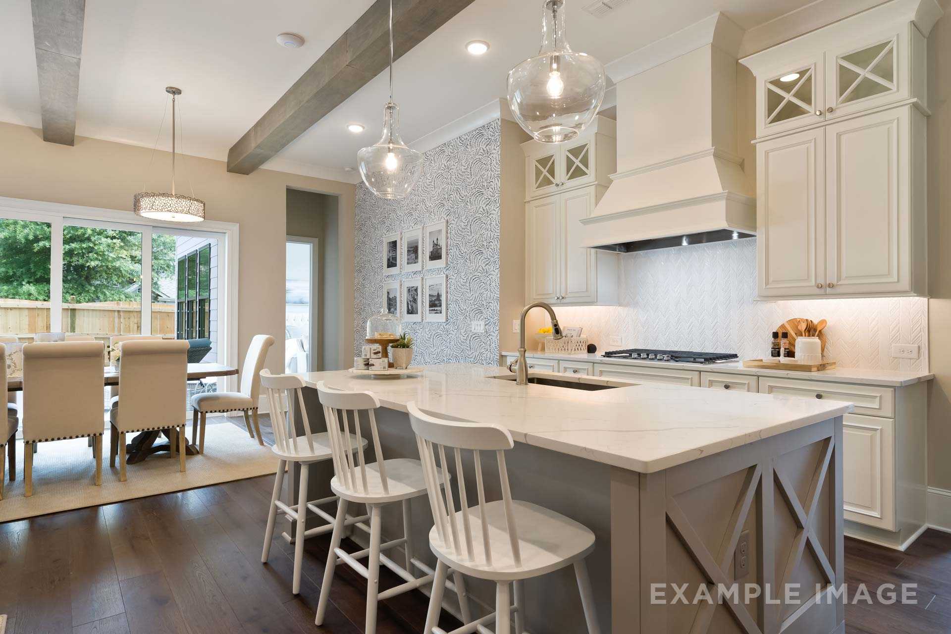 Spacious gourmet kitchen in The Seaside home with white shaker cabinets, gray subway backsplash, large island, and adjacent dining area