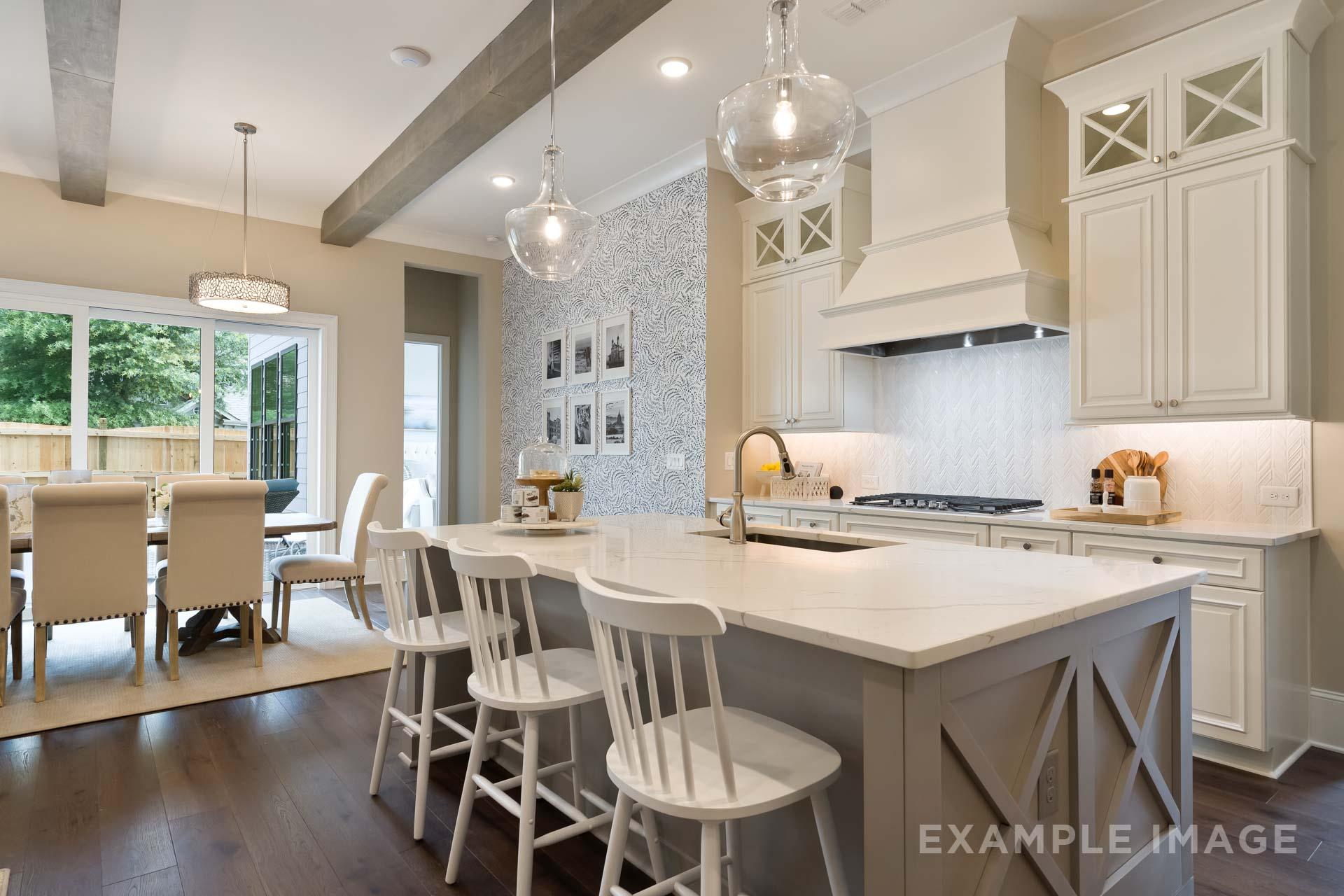 Gourmet kitchen in The Seaside C featuring white shaker cabinets, large island with bar stools, farmhouse sink, and open dining area