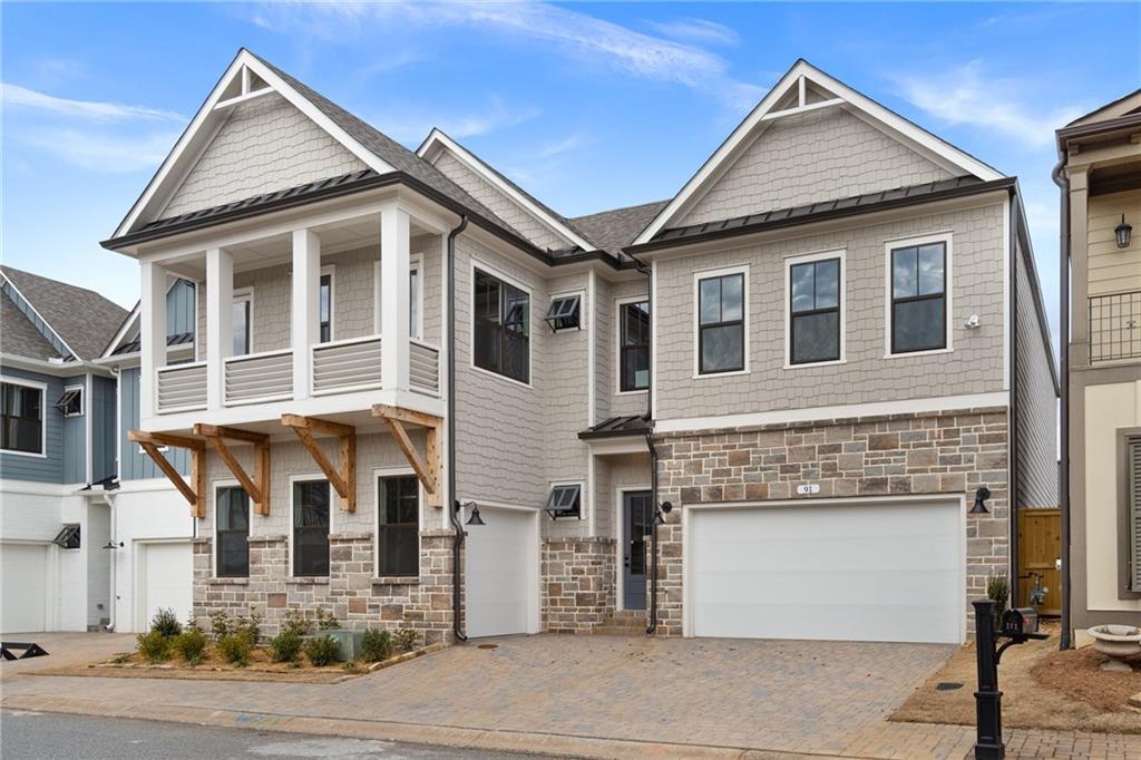 Modern 2-story Seaside B home exterior with stone accents, balcony, and 3-car garage in The Village at Towne Lake, Woodstock, Georgia