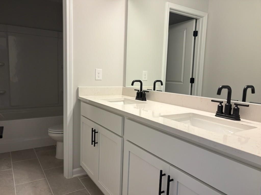 Modern double vanity bathroom with quartz counters, black faucets, and soaking tub in Davidson Homes Hickory B, Winder, GA