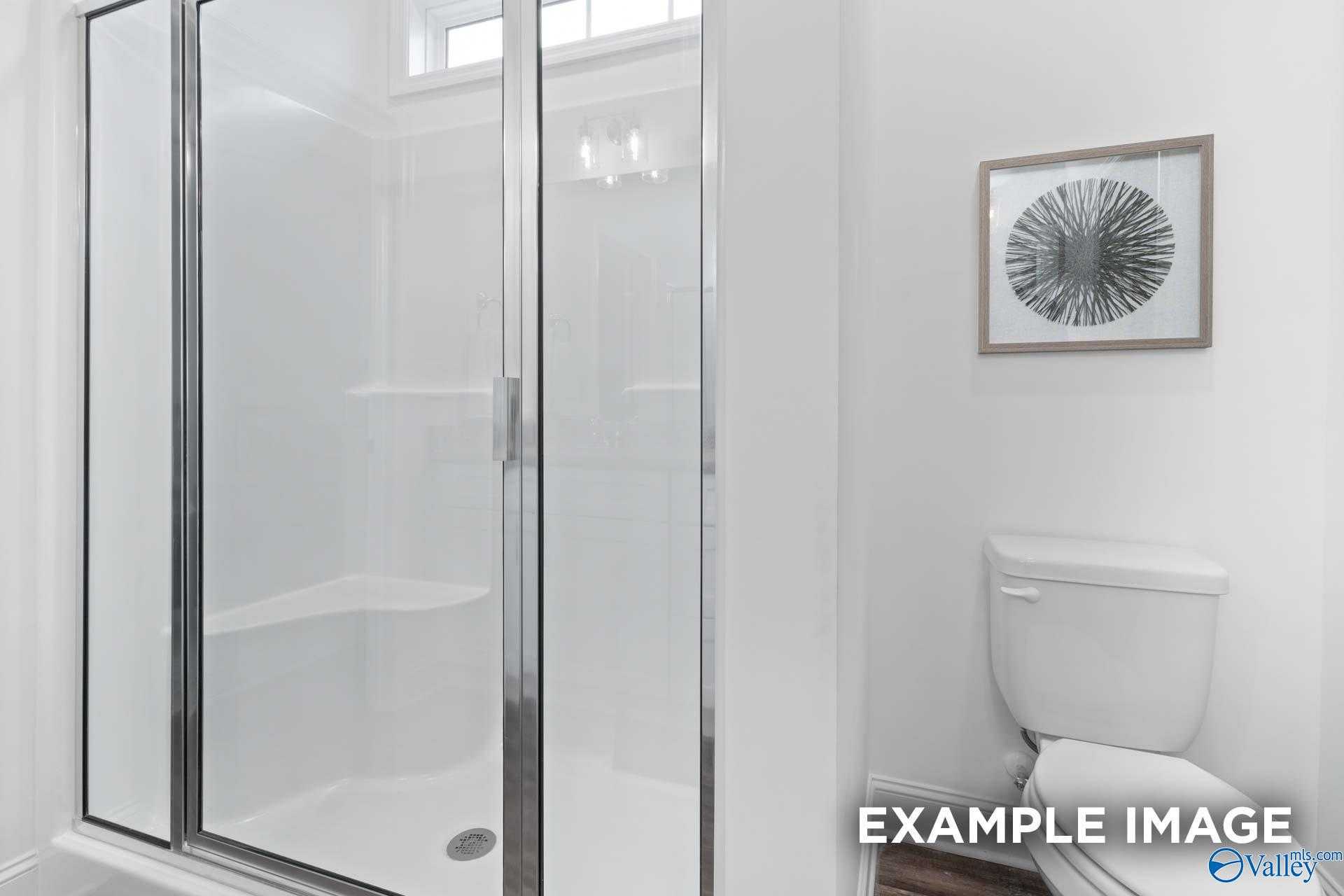 Modern master bathroom featuring frameless glass shower, white tile, and toilet in Davidson Homes The Cumberland, Decatur, Alabama