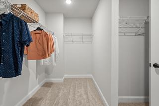 Spacious master walk-in closet in The Washington H townhome with wire shelving, hanging apparel, and light wood flooring