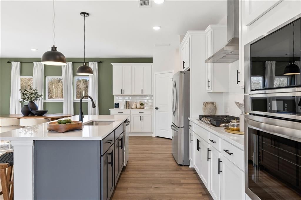 Modern kitchen with white cabinets, gray island, and stainless appliances in The Rabun B floor plan at The Bluffs, Canton.