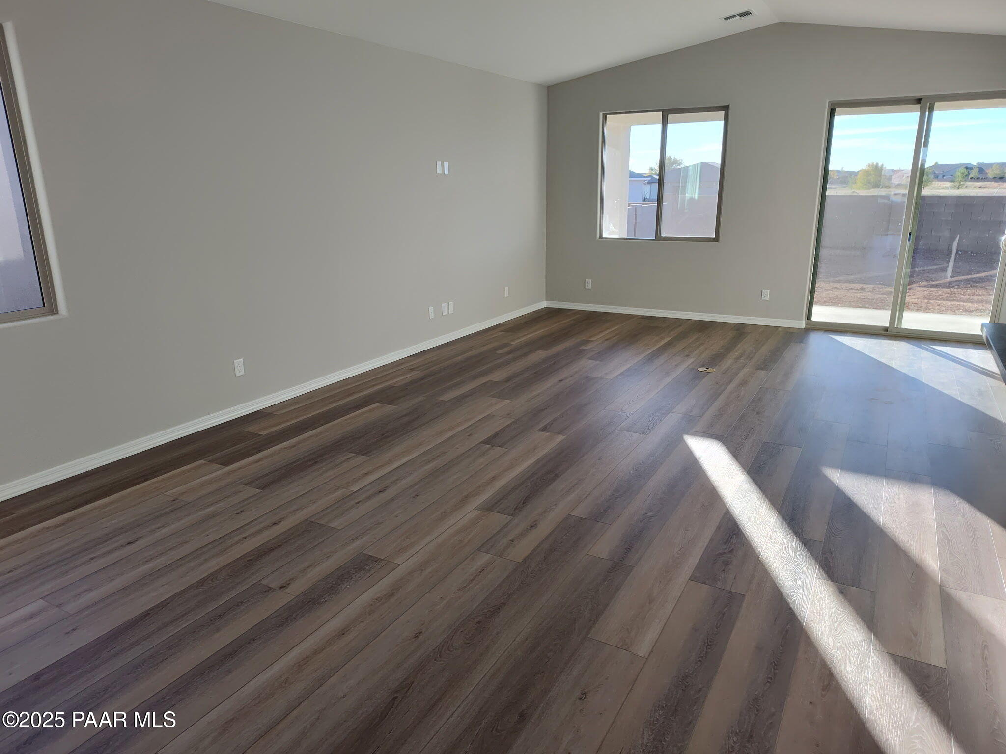 Bright spacious living room with vaulted ceiling, large windows, sliding patio doors, and luxury vinyl plank flooring in Davidson Homes The Frontier C, Prescott Valley