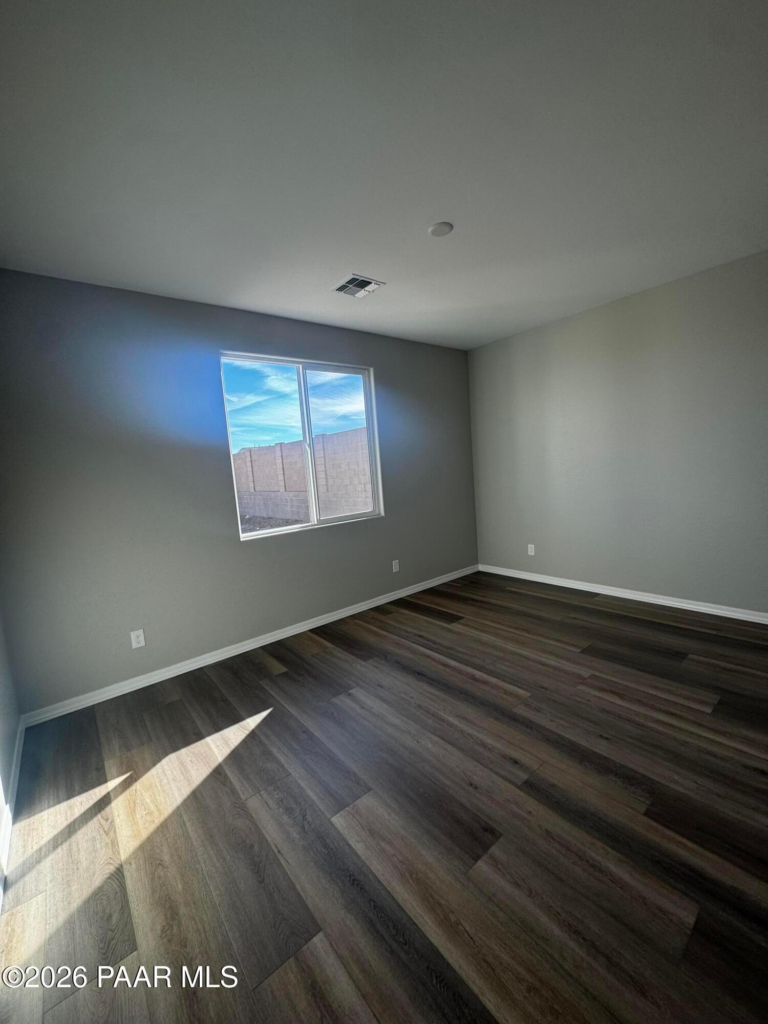 Bright empty bedroom featuring gray walls, large sunny window, and luxury vinyl plank flooring in Davidson Homes The Daybreak B, Prescott, AZ